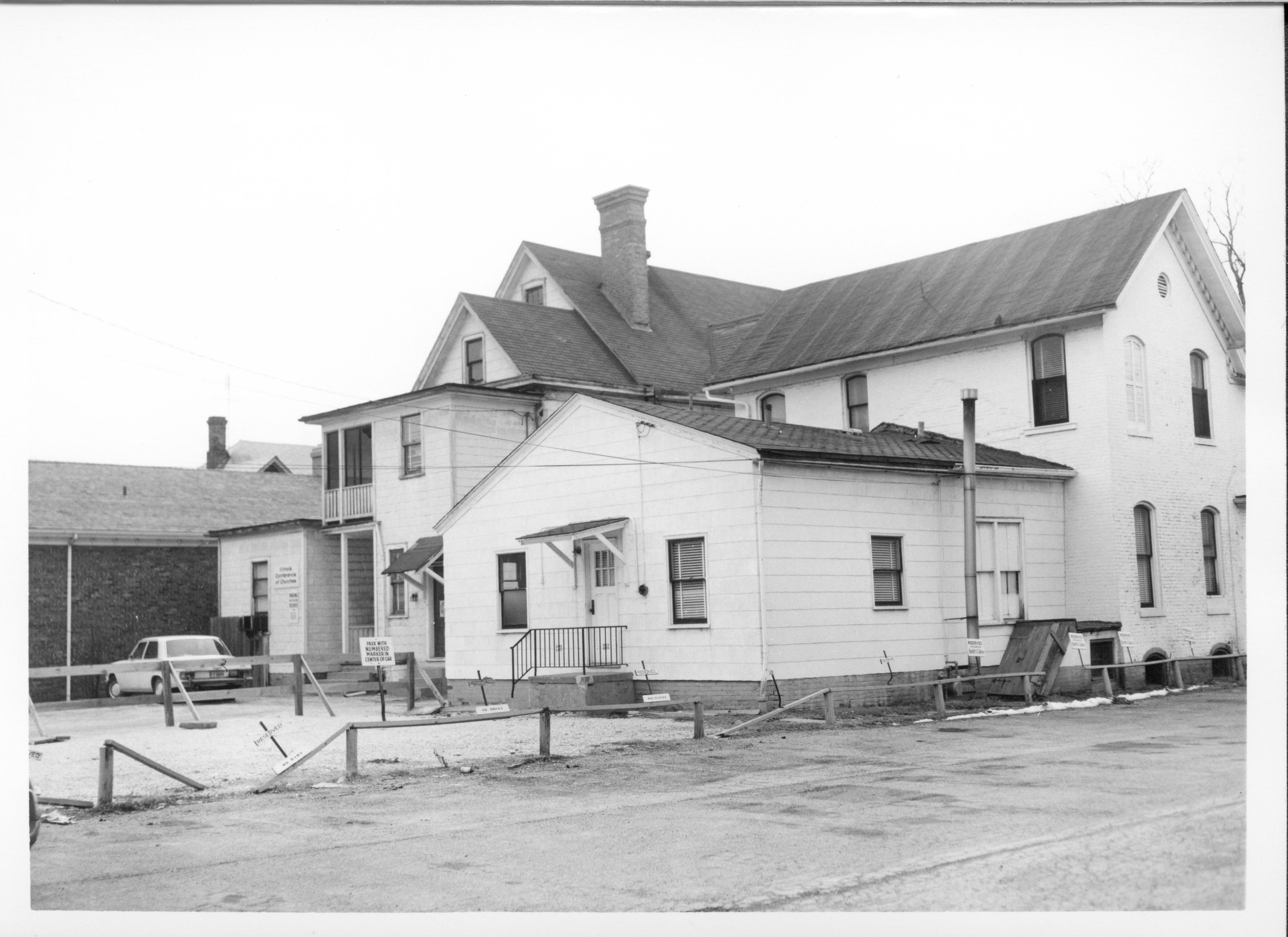 Homes belonging to Dr. Albert T. Kwedar (right), Eugene McNally (center), and Evelyn Grummon (left) on Block 7, Lots 4-6 along 7th Street. Area is now Visitor Center and bus parking lot/Grace Lutheran Church parking lot. Looking Southwest along 7th Street south of Capitol Ave. Visitor Center, parking lot, Kwedar, McNally, Grummon