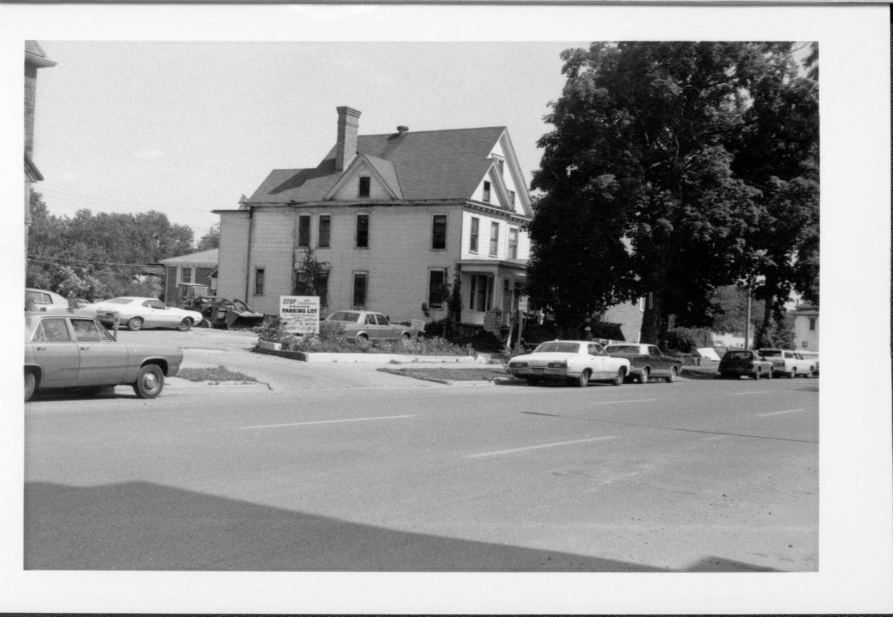 House belonging to Eugene McNally, Block 7, Lot 5 along 7th Street in area where Visitor Center is now.  Grace Lutheran Church parking lot is on left.  7th Street in foreground.  Scoop seen near house is clearing debris from house being razed. Looking southeast McNally, Grace Lutheran Church, 7th Street, Visitor Center