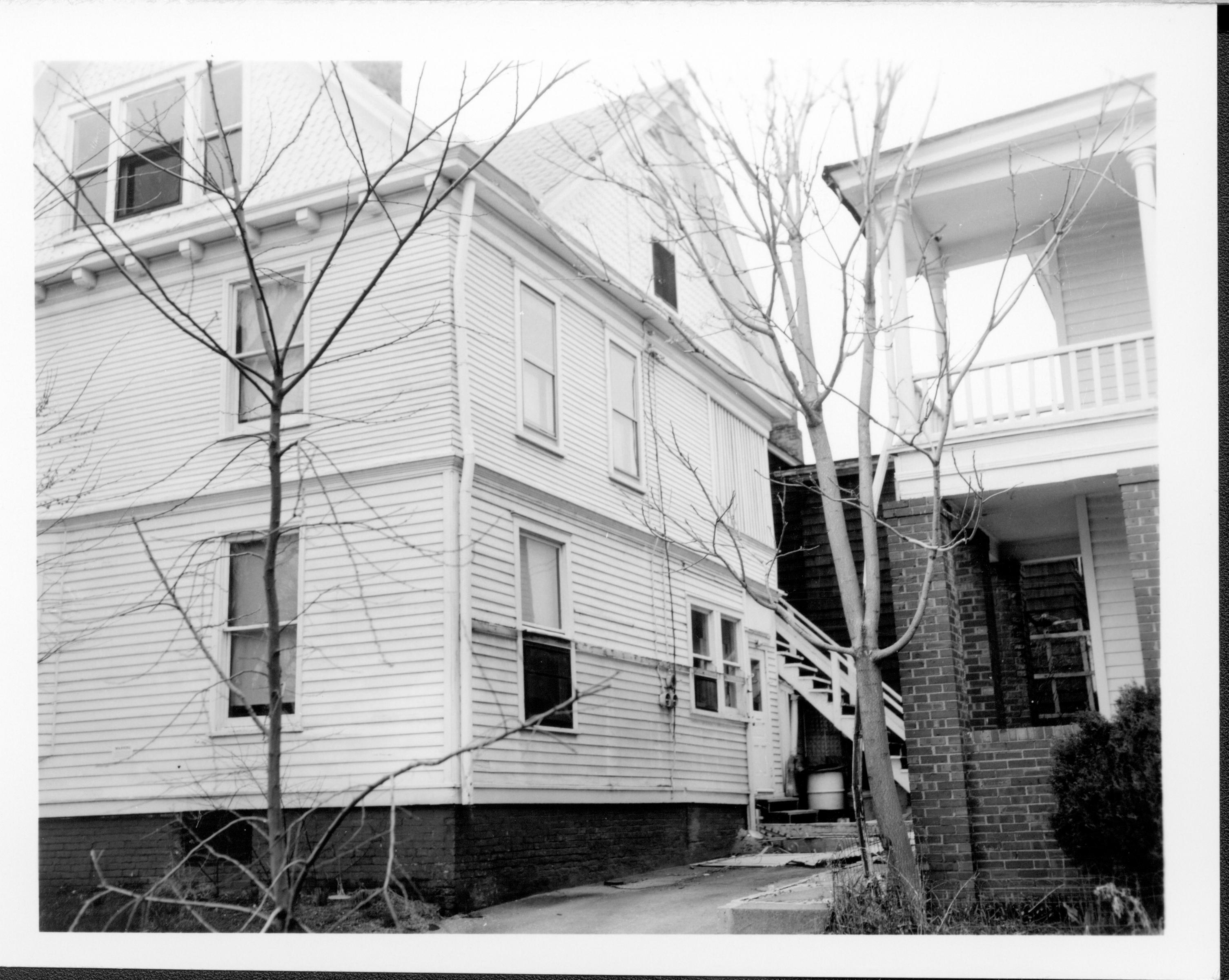 Home on left owned by William Hermes in use as apartments, Southeast corner, Block 7, Lot 8 along Jackson Street.  Home on right owned by Hugh Garvey in use as apartments. Now area is Visitor Center. Looking North from Jackson Street with narrow parking area inbetween buildings. Hermes, Garvey, Visitor Center, Jackson Street