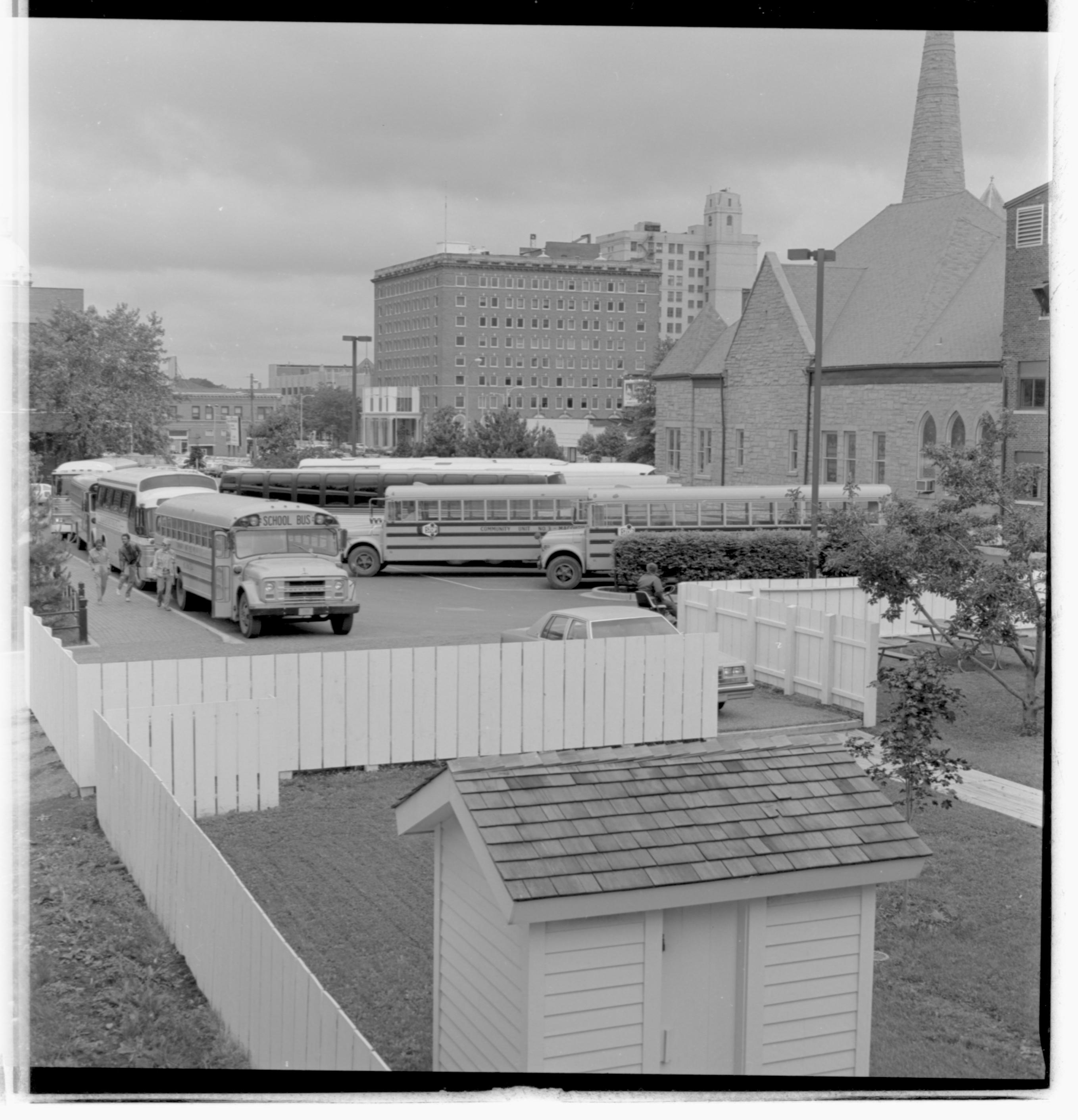 Parking lots - Bus lot, Grace Lutheran Church on right, Lyon House shed in foreground, former Leland Hotel in background, maintenance staff on mower in alley looking Northwest Bus, Parking Lot, Grace Lutheran Church, Lyon Shed