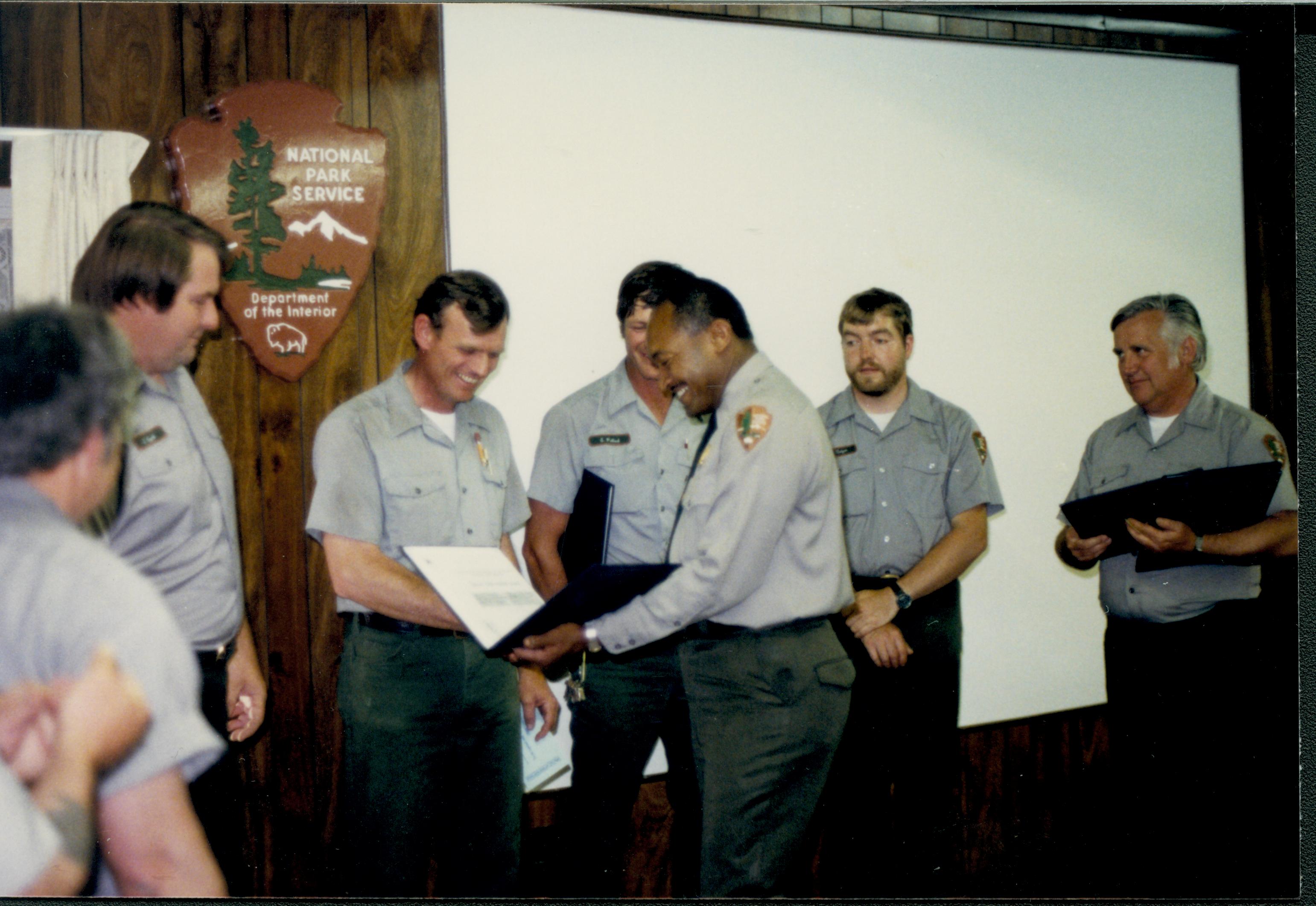 Supt. Gentry Davis giving out special achievement awards to Maint. staff in Conference Center. Bob Trenter laughing while receiving award. Looking West on second floor awards, staff, Conference Center