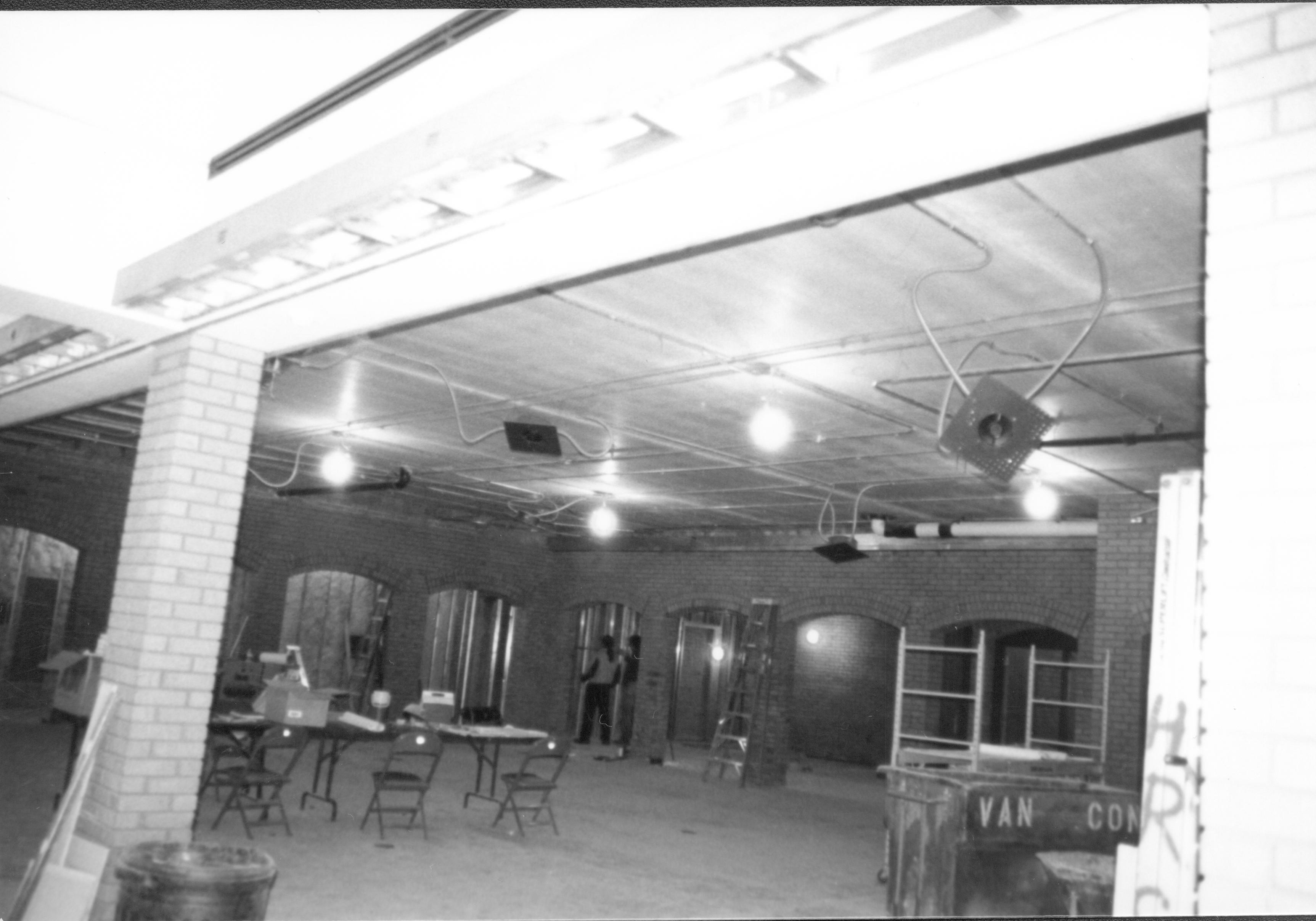Visitor Center - remodeling, ceiling structure. Eastern National staff(?) checking storage area in background. Tables and chairs set up in main area. Restroom arches in background left. Door to office in background right. Looking North from South entrance area. Visitor Center, remodeling, bookstore, Eastern National, main, restrooms, office