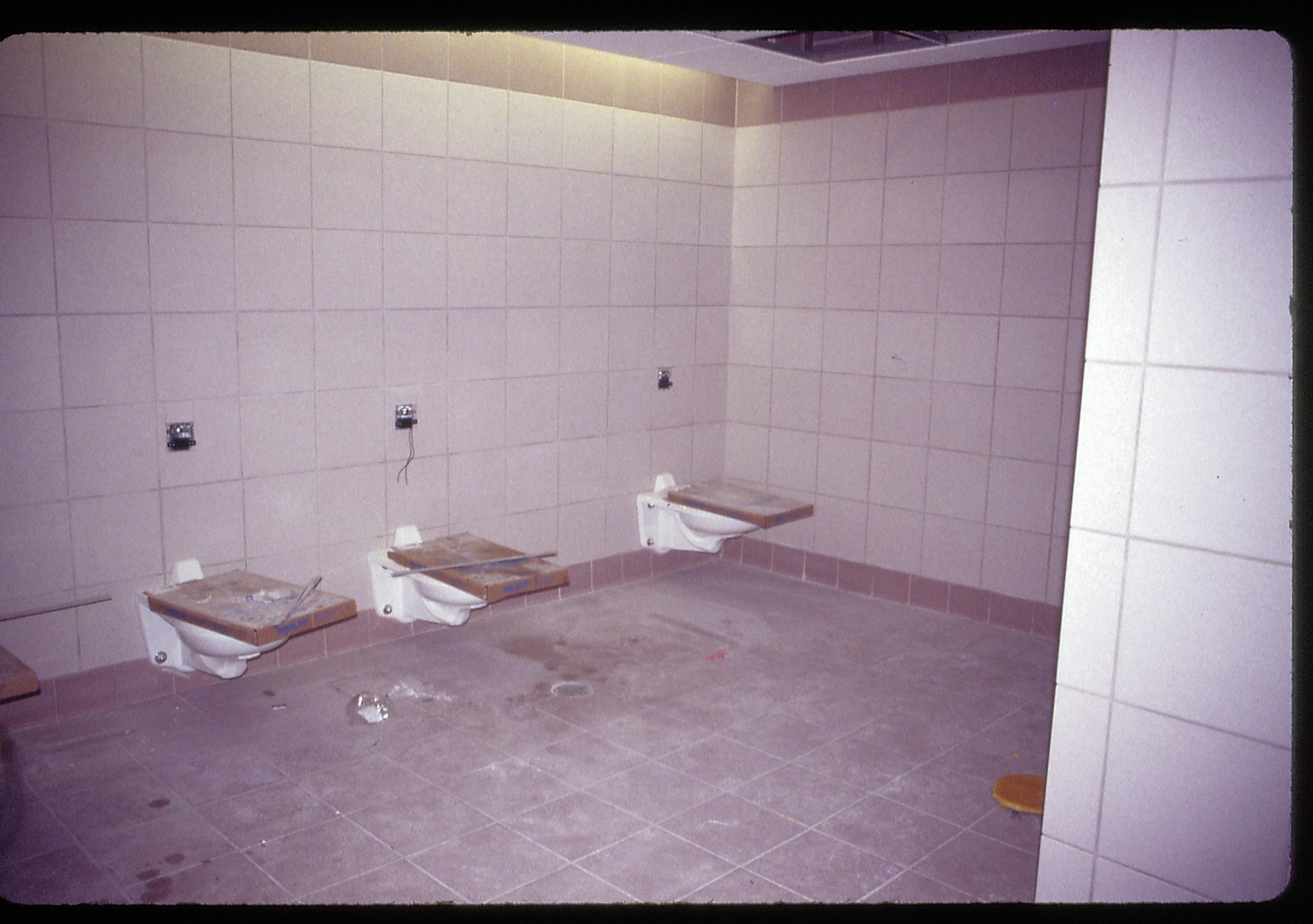 Visitor Center - remodeling. Toilets in Women's restroom before stalls installed. Tile walls and contrasting color tile floors and baseboard visible. Toilet seats remain in cardboard shipping boxes on top of toilets. Looking Northwest from doorway of Women's restroom Visitor Center, remodel, restroom, toilets, tile