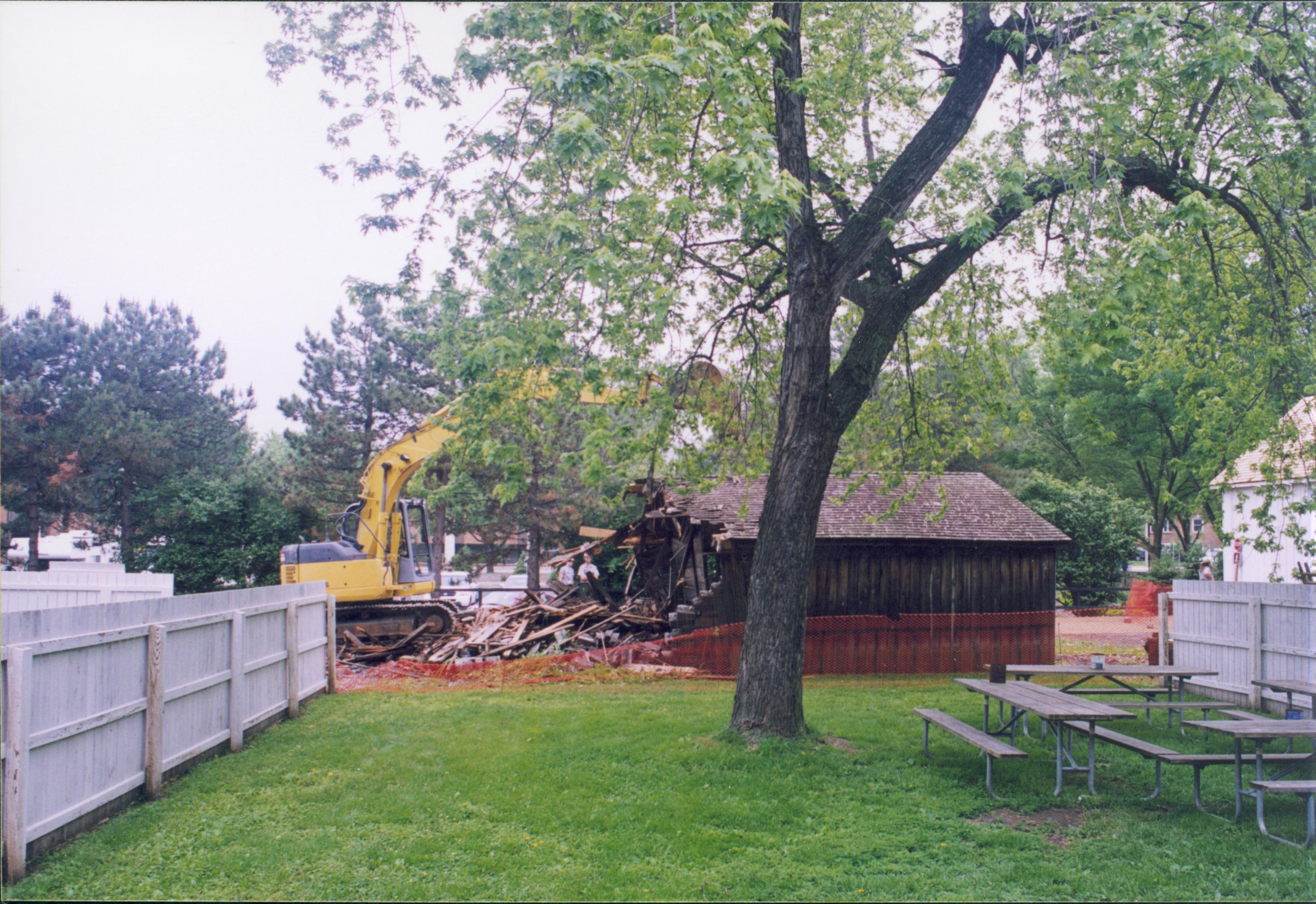 Maintenance Shed removal - Sprigg shed tear down commences on non-historic barn. Maintenance Work Leader Vee Pollock operates crane. New Corneau Barn in background far right. Visitor Parking lot in background with visitors just visible behind shed. Looking West from Sprigg backyard. Sprigg, shed, demolition, Corneau Barn, parking lot