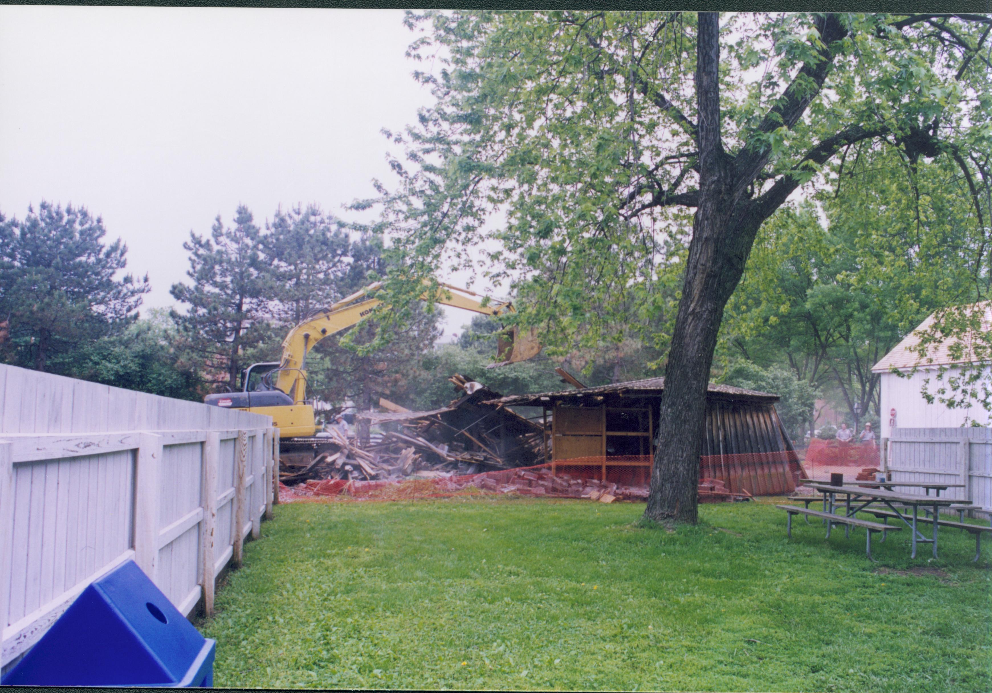 Maintenance Shed removal - Sprigg shed tear bown on non-historic barn. Maintenance Work Leader Vee Pollock operates crane. New Corneau Barn in background far right. Rangers David Wachtveitl and Christy Lindberg watch in far background right. Visitor Parking lot in far background. Looking West from Sprigg backyard Sprigg, shed, demolition, Corneau Barn, staff, parking lot