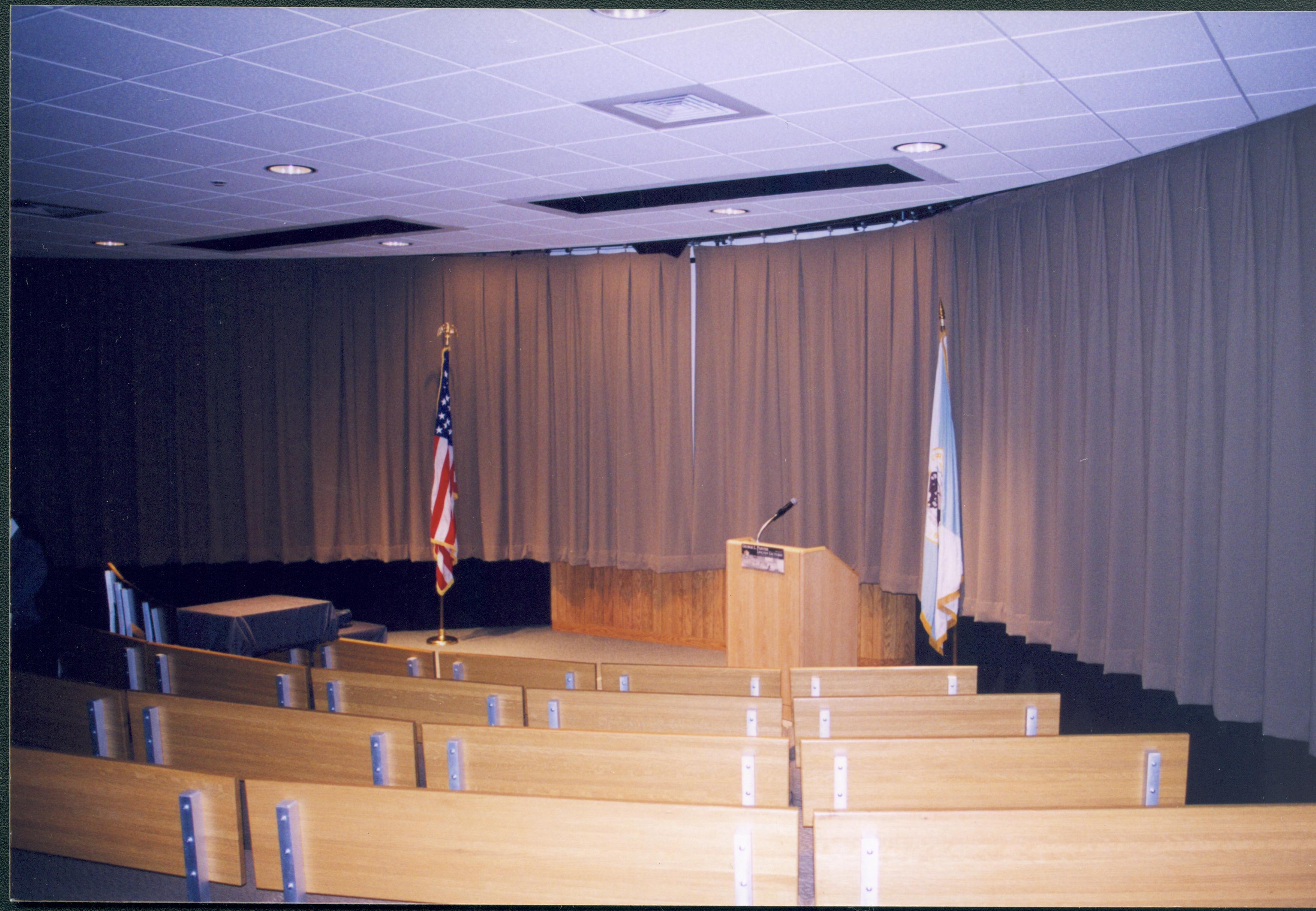 Lincoln's Birthday - Theatre 1 in the Visitor Center set up for lectures including a slide projector set up over top of seats on left and a podium with a special birthday lectures sign in front, flanked by the US flag and a DOI flag.  Looking South from Theater 1 entrance Lincoln's Birthday, Theater 1, Visitor Center, flags, AV setup