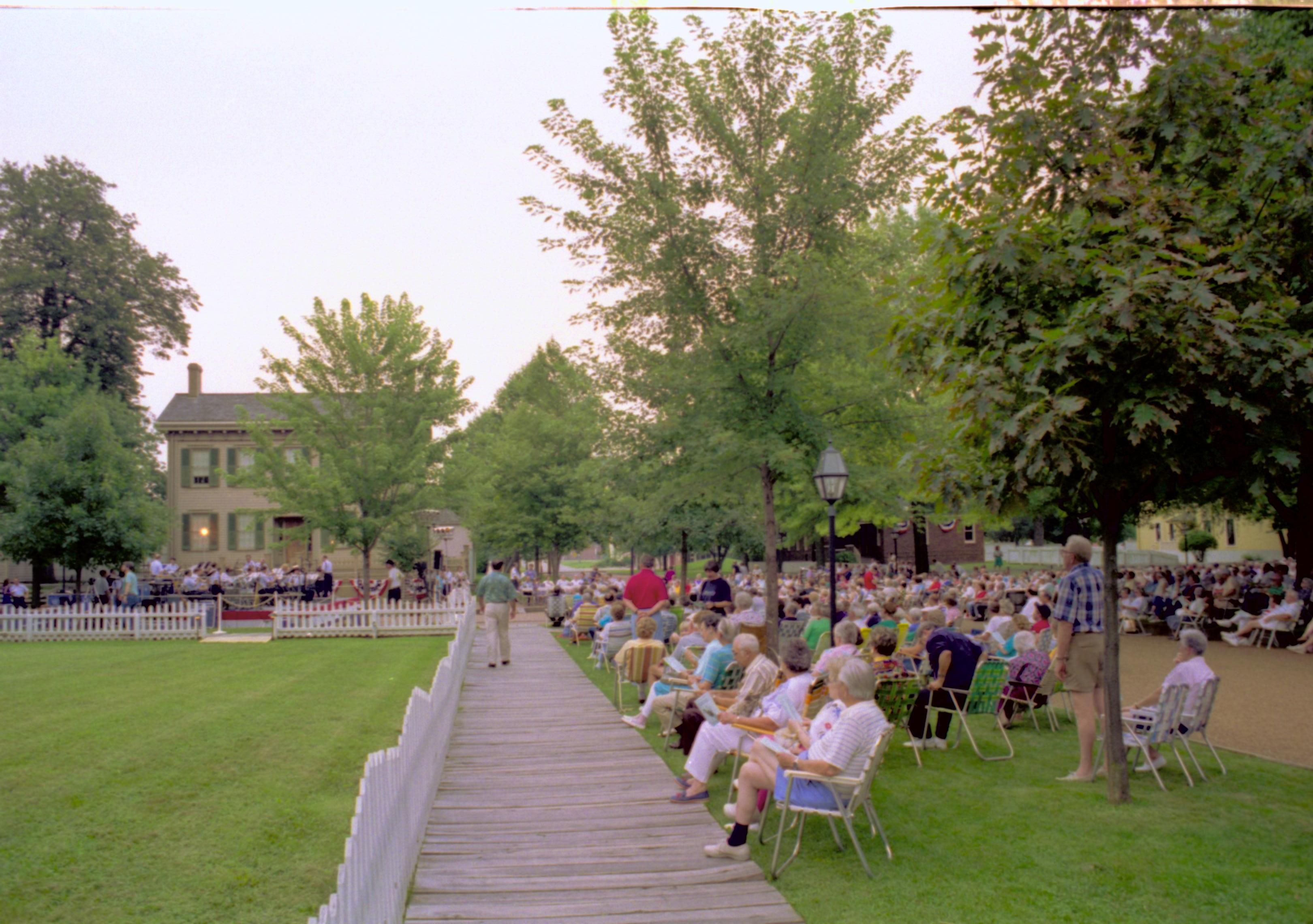 People seated listening to Coast Guard band with Lincoln home in background. Lincoln Home NHS- Coast Guard Band Concert, 267618 concert, Coast Guard