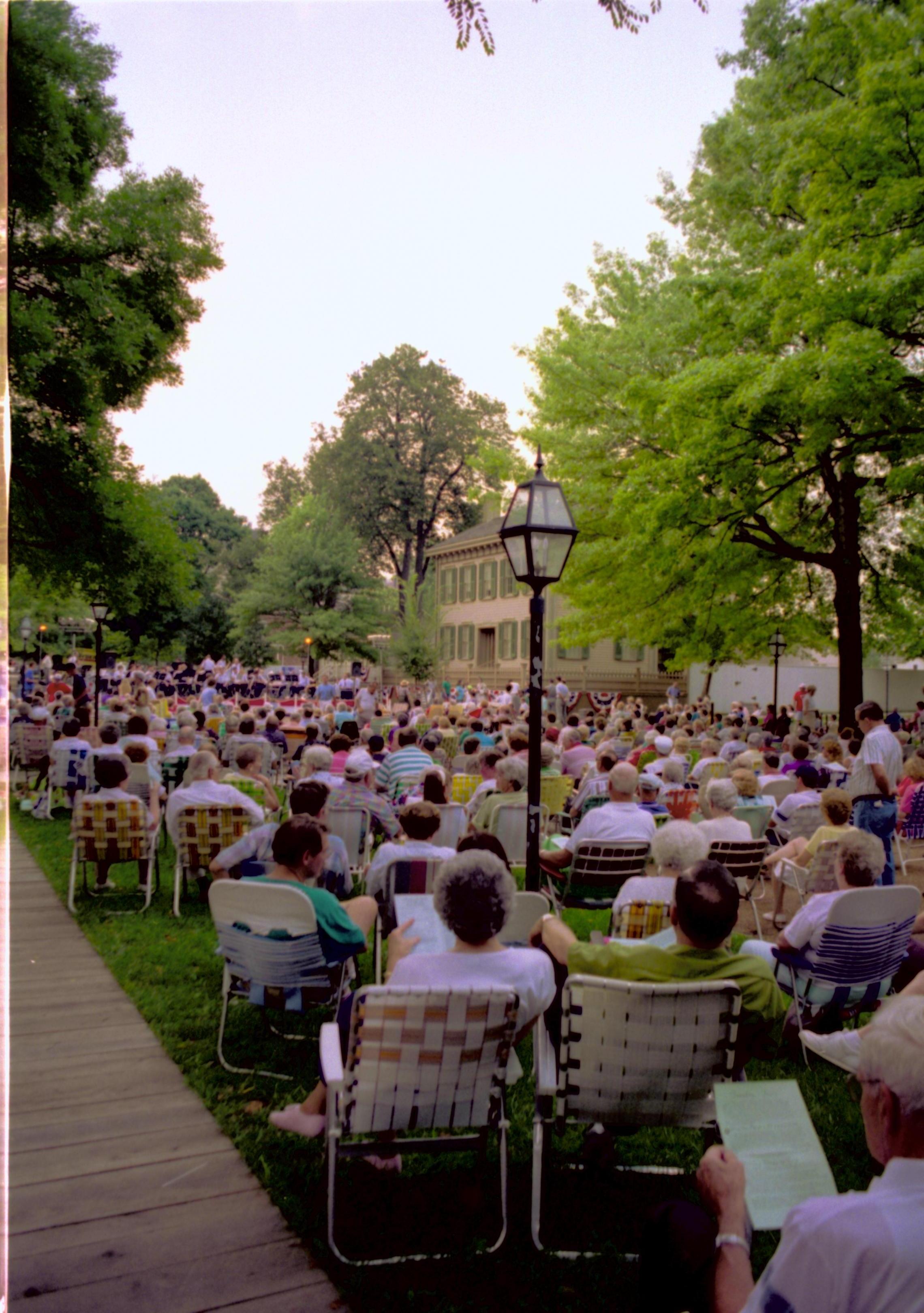 People seated listening to Coast Guard band with Lincoln home in background. Lincoln Home NHS- Coast Guard Band Concert, 267618 concert, Coast Guard