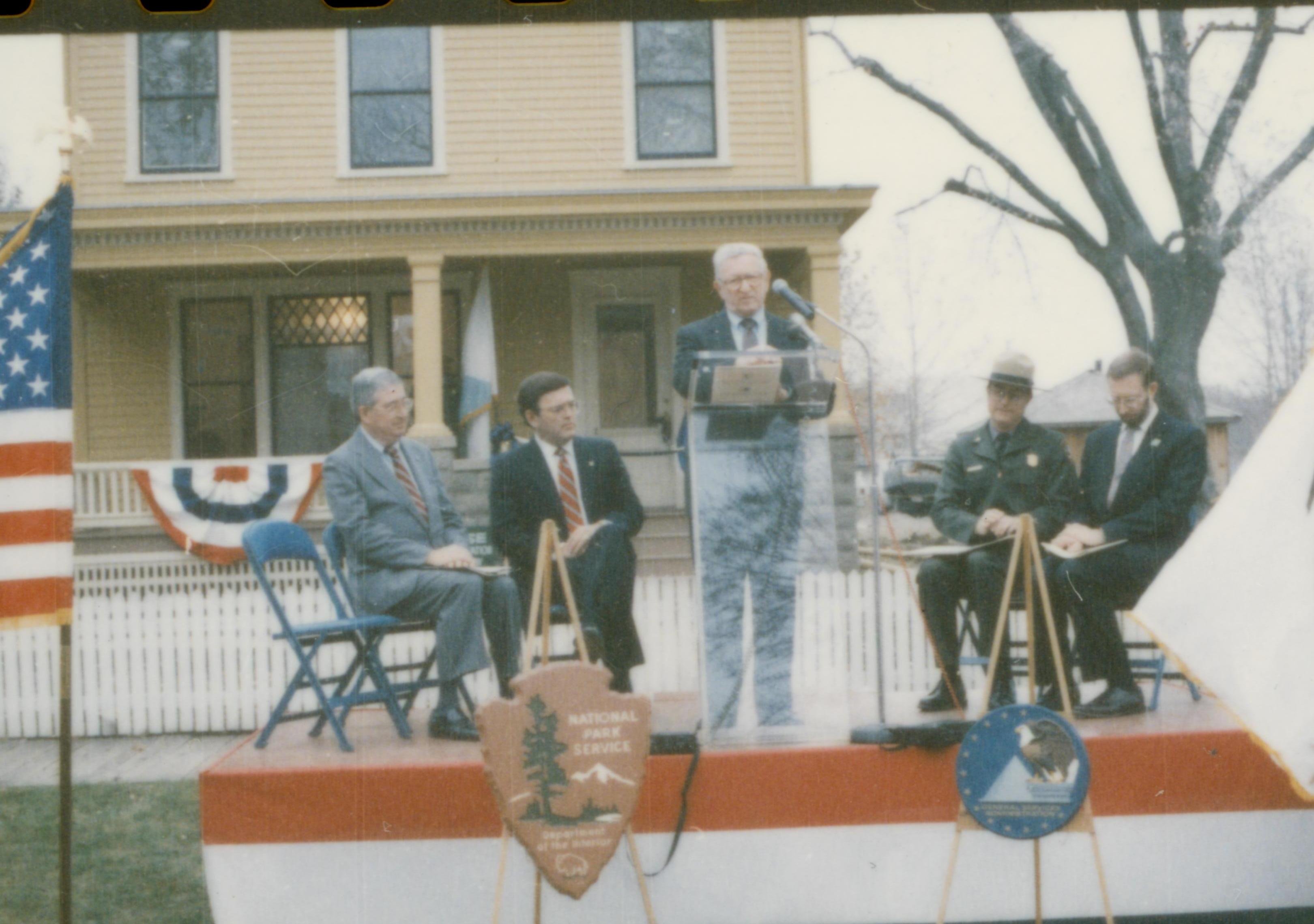 Five men on speakers platform in front of Cook house Lincoln Home NHS- Cook House Re-opening, 1 Cook, ceremony