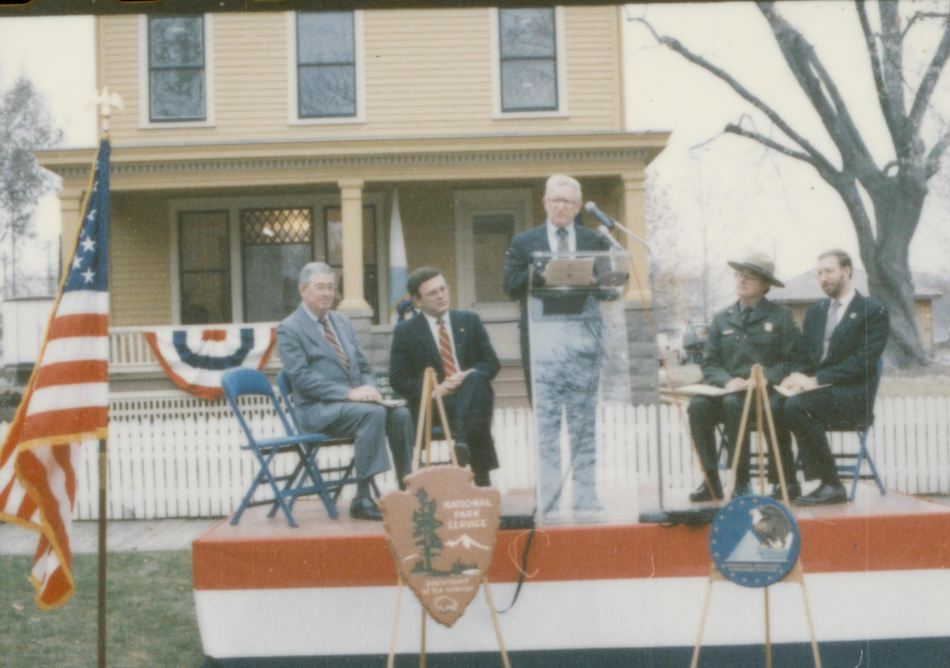 Five men on speakers platform in front of Cook house Lincoln Home NHS- Cook House Re-opening, 1 Cook, ceremony