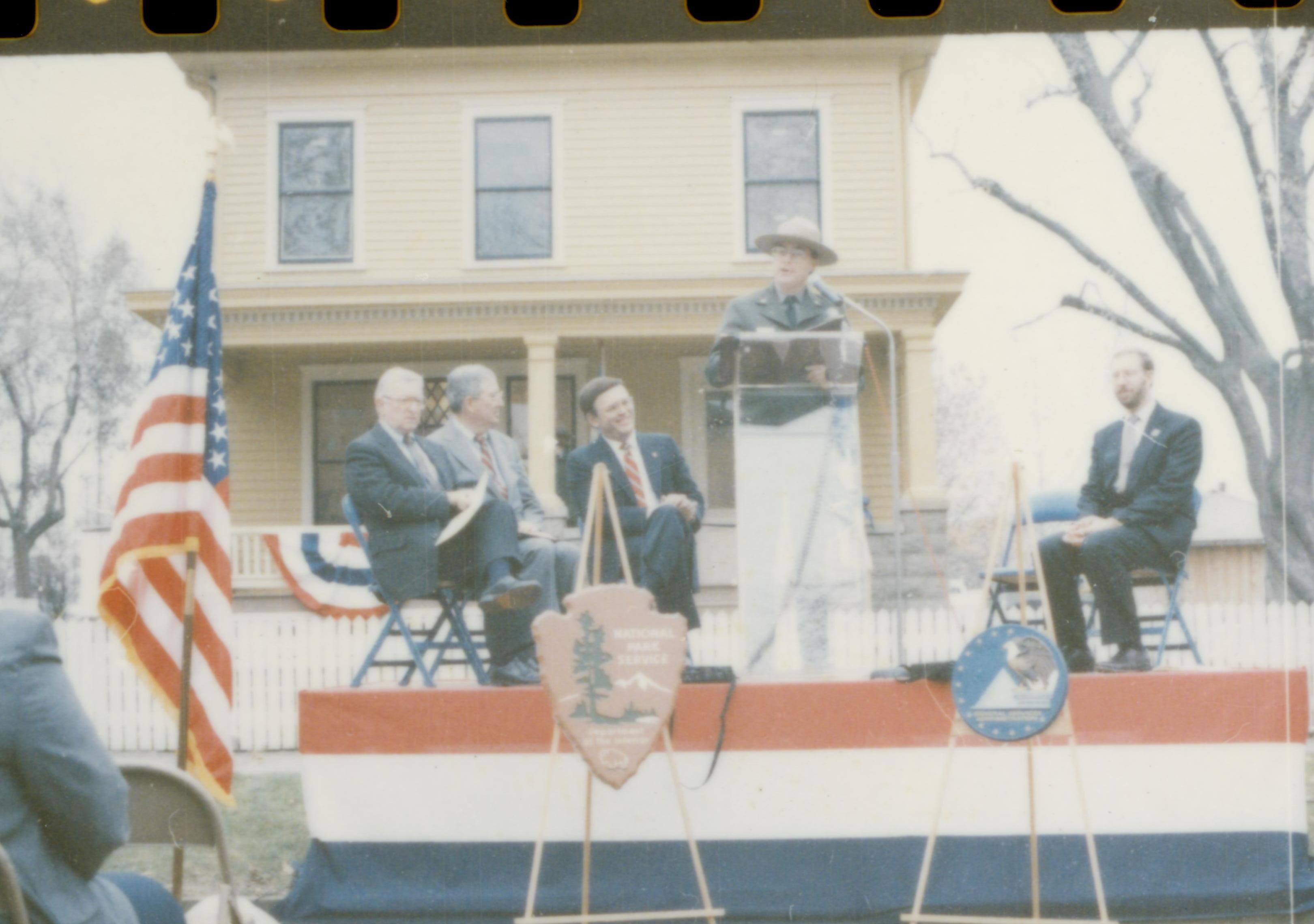 Five men on speakers platform in front of Cook house Lincoln Home NHS- Cook House Re-opening, 1 Cook, ceremony