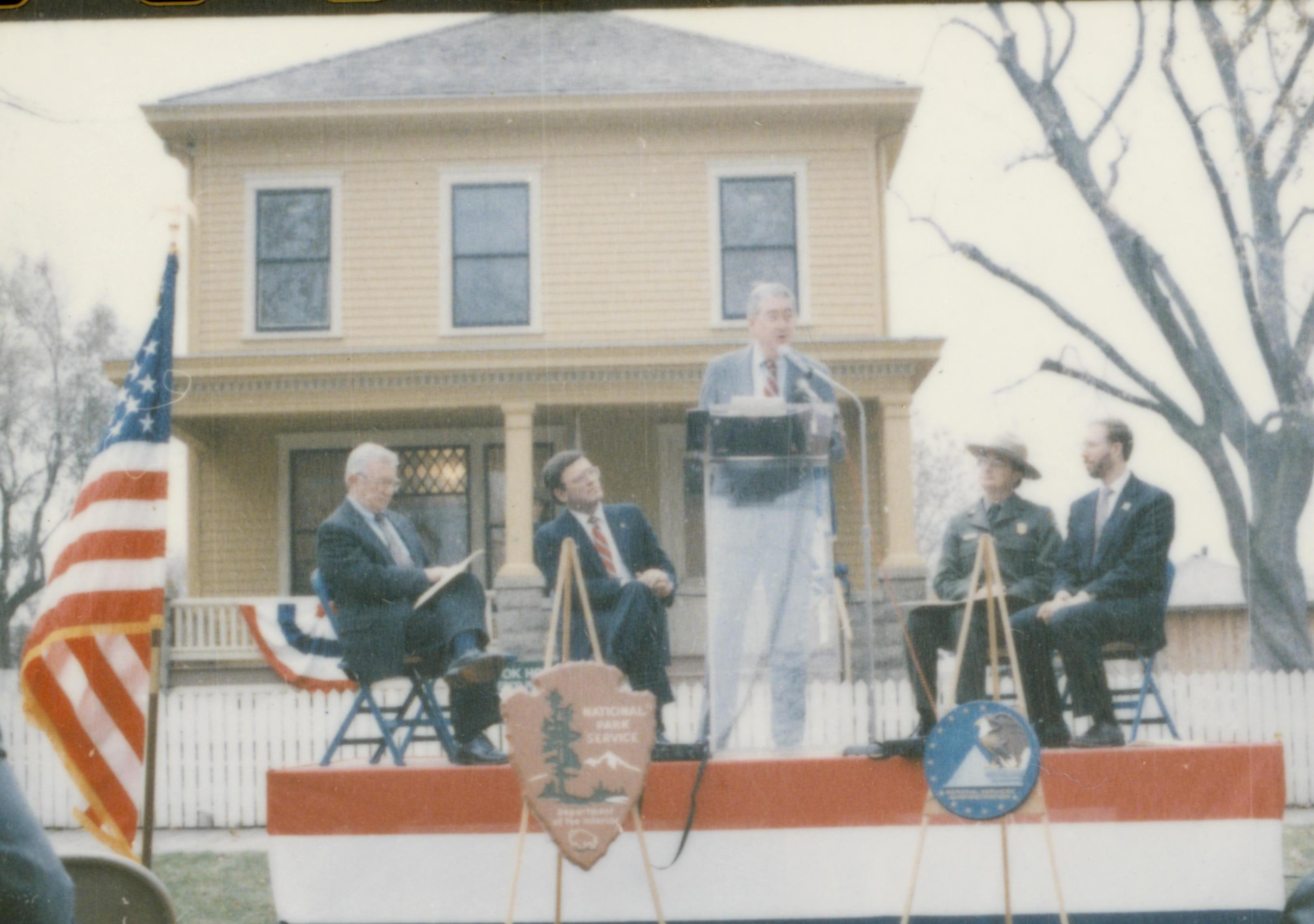 Five men on speakers platform in front of Cook house Lincoln Home NHS- Cook House Re-opening, 1 Cook, ceremony