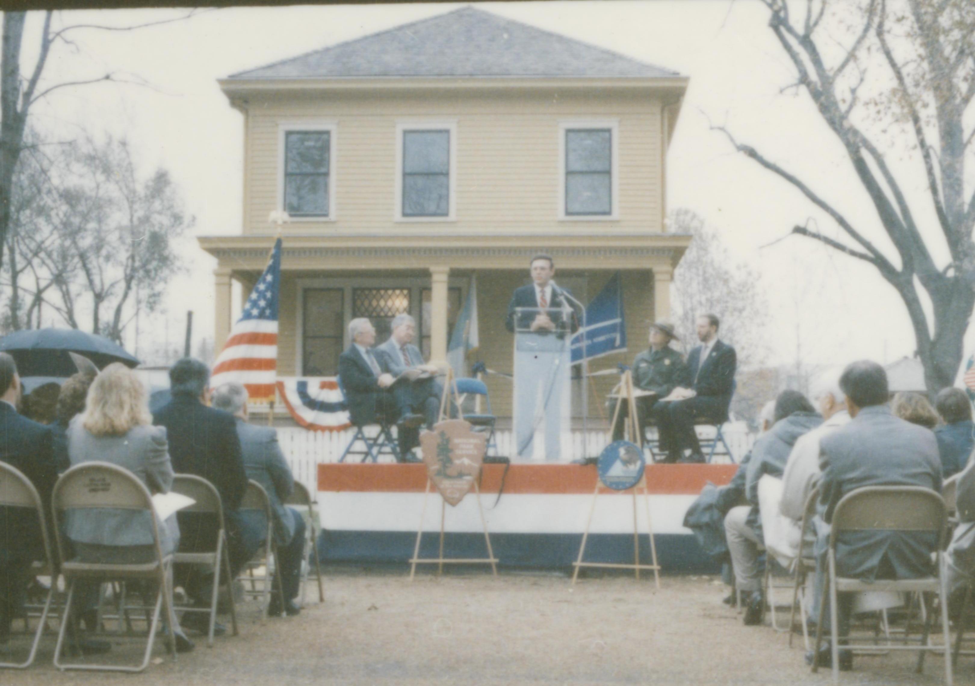 Five men on speakers platform in front of Cook house Lincoln Home NHS- Cook House Re-opening, 1 Cook, ceremony