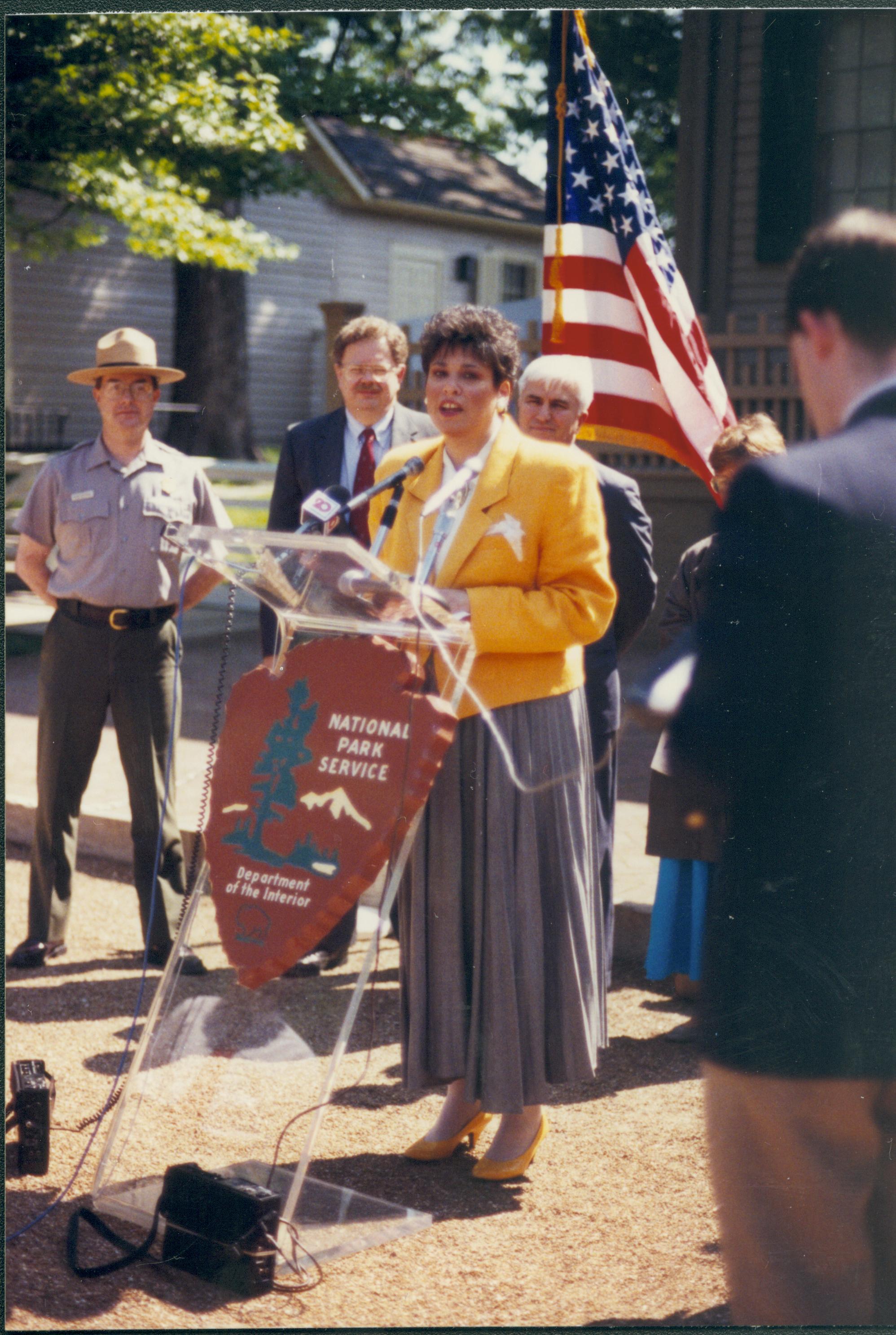 Lady speaking with others standing behind her. Lincoln Home NHS- Durbin 3581381 conference, media, interview