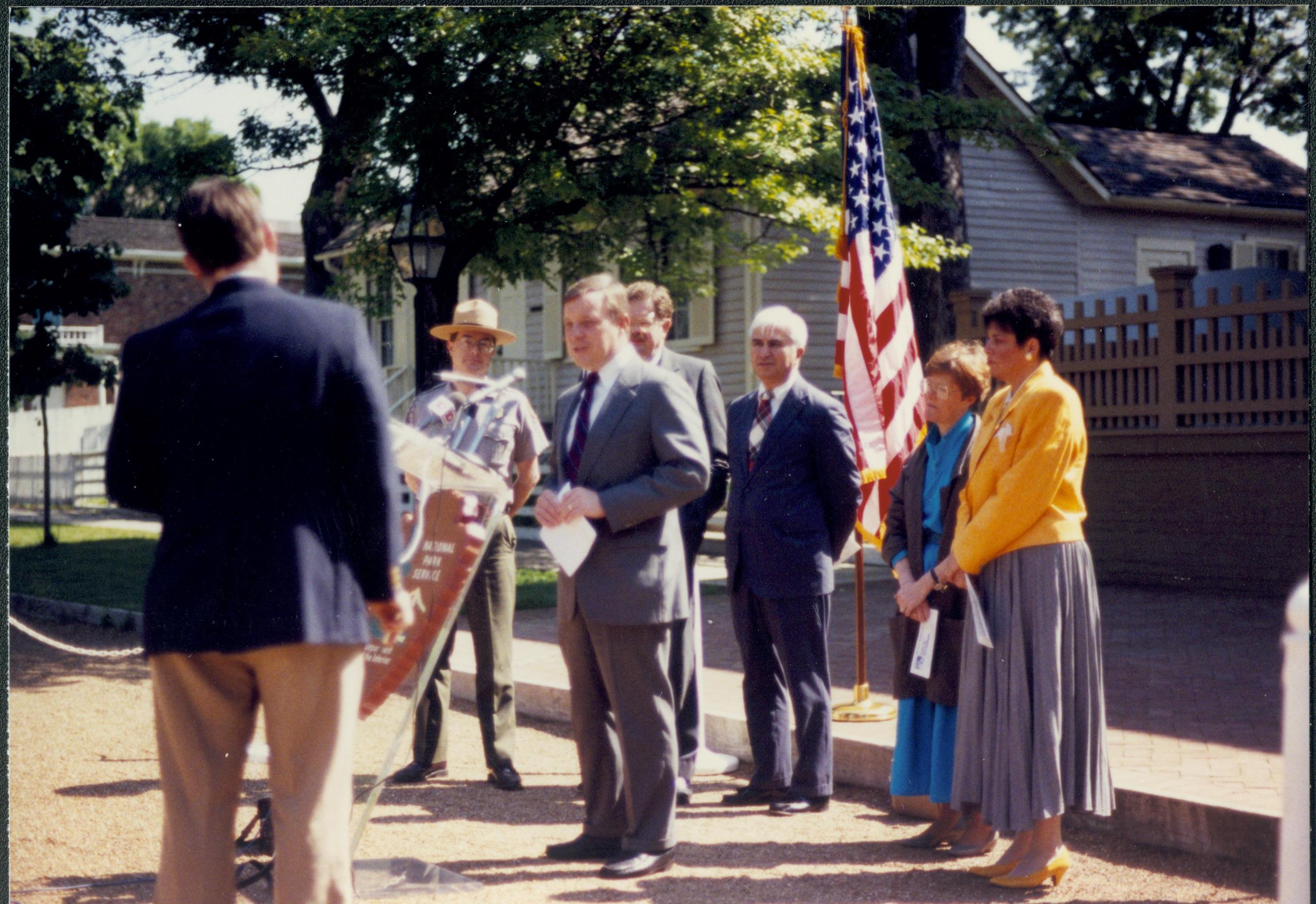 People standing around podium in front of Home. Lincoln Home NHS- Durbin 3581381 interview, conference