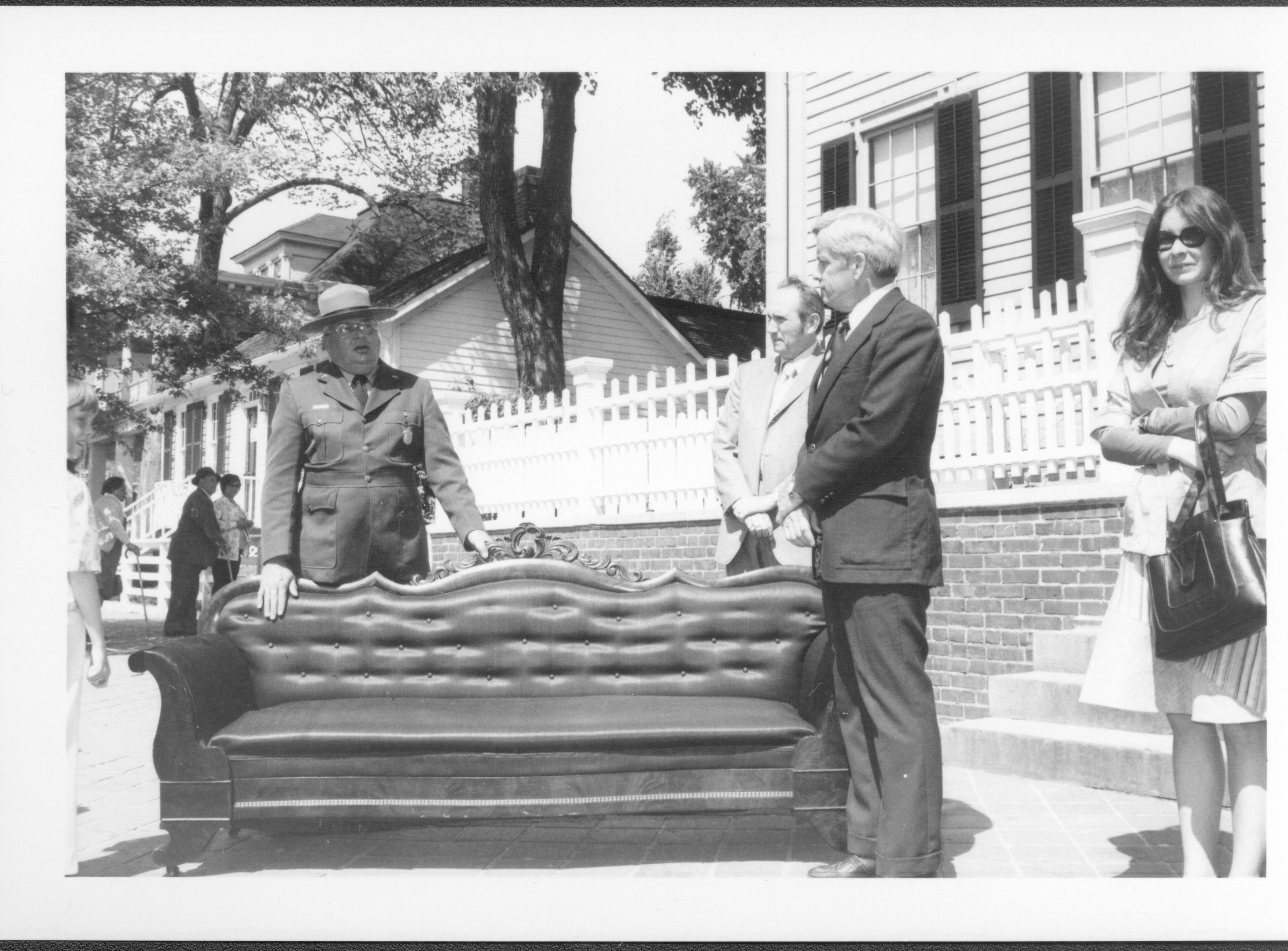 Three men and a lady standing around sofa on sidewalk. Lincoln Home NHS- Bring Furniture Back Home, neg #12 class #1190, class 8 pic 12 furniture, return