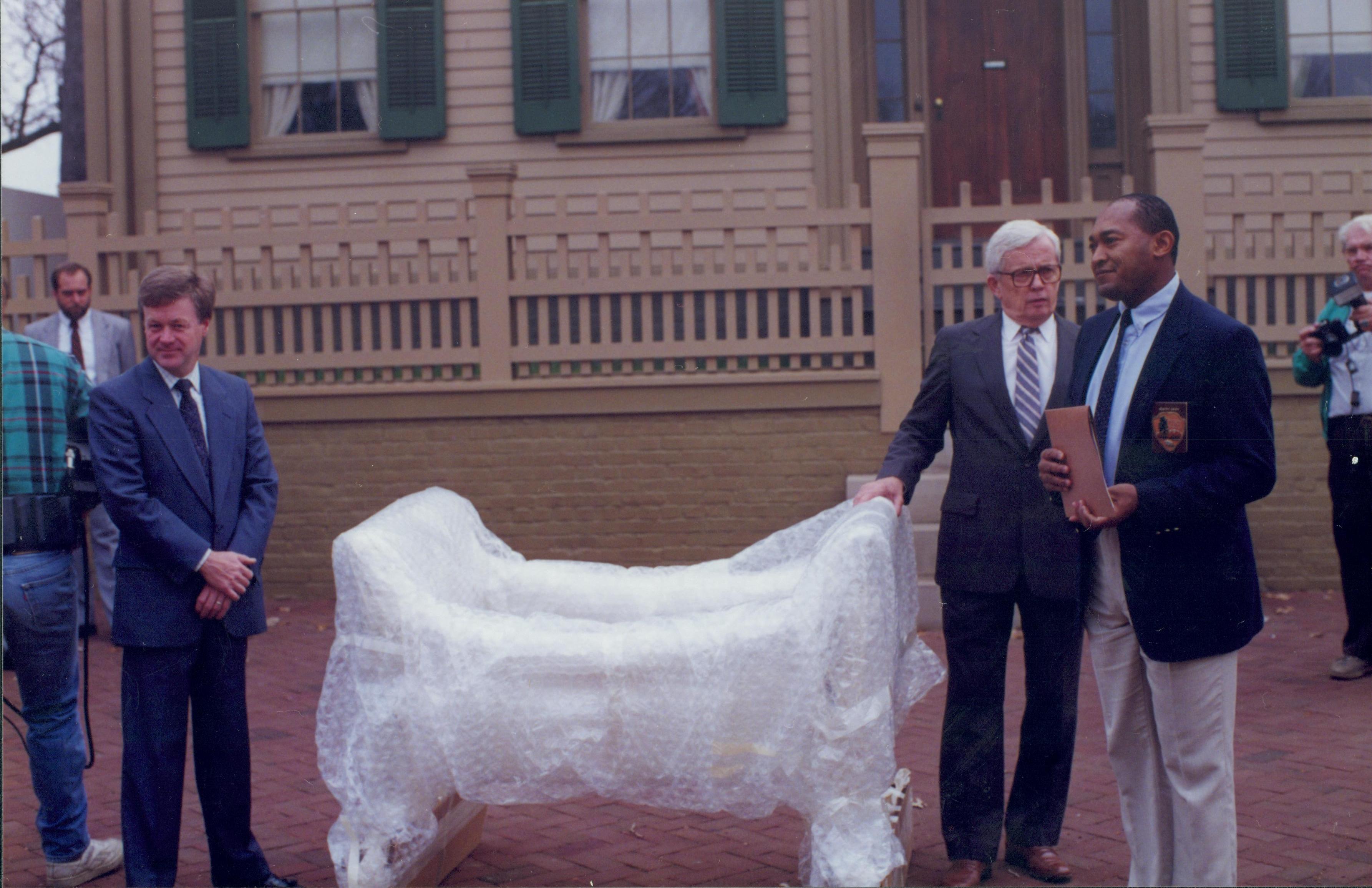 Three men standing around wrapped piece of furniture. Lincoln Home NHS- Bring Furniture Back Home furniture, movers