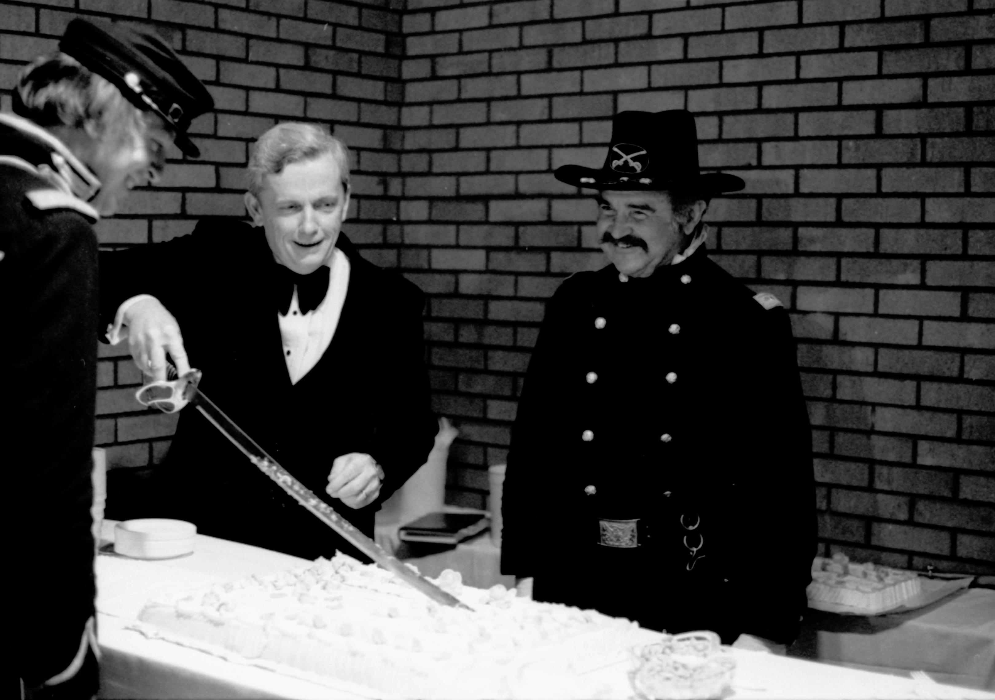 Man cutting cake with a sword. Lincoln Home NHS- Paul Findley visit to LIHO Finley, visit, reception