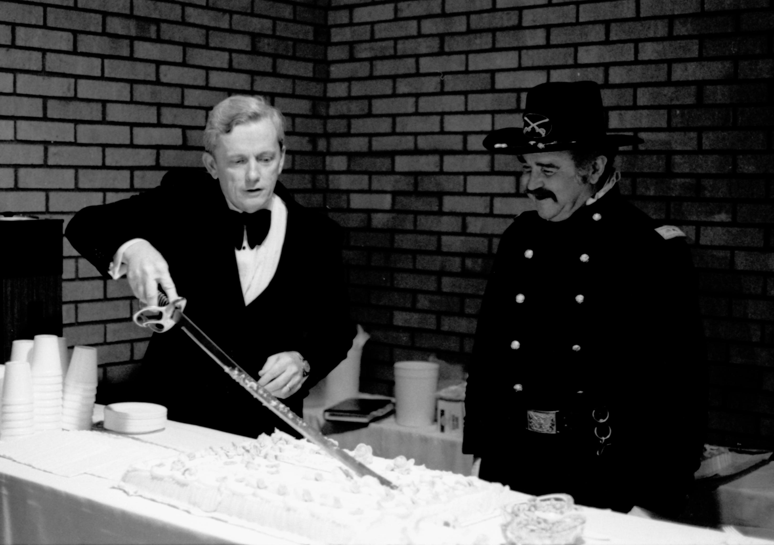 Man cutting cake with a sword. Lincoln Home NHS- Paul Findley visit to LIHO Finley, visit, reception