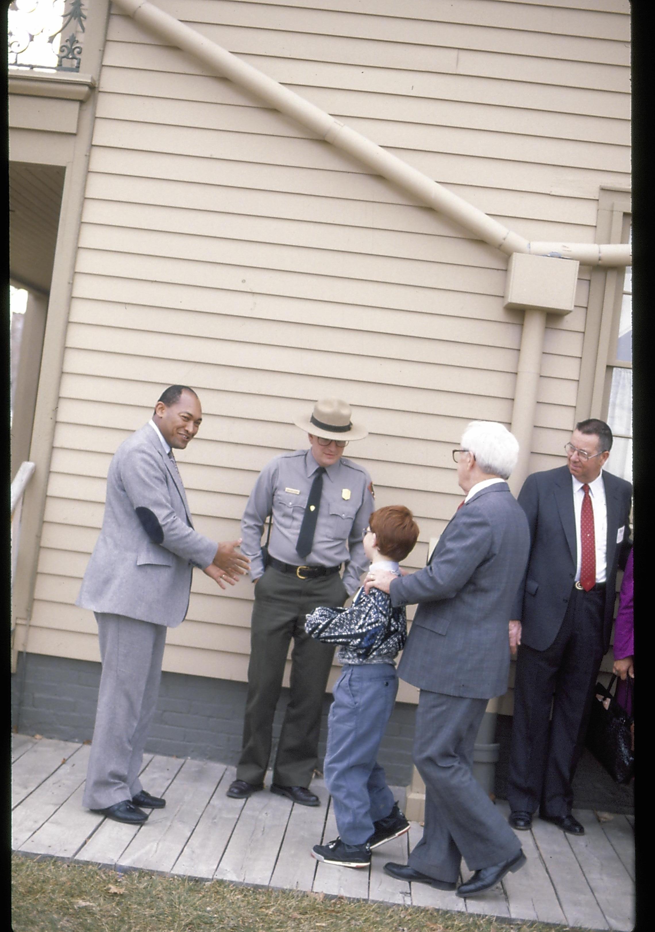 Men standing at rear of home with small boy. Lincoln Home NHS- Paul Findley Recognition Award Finley, award