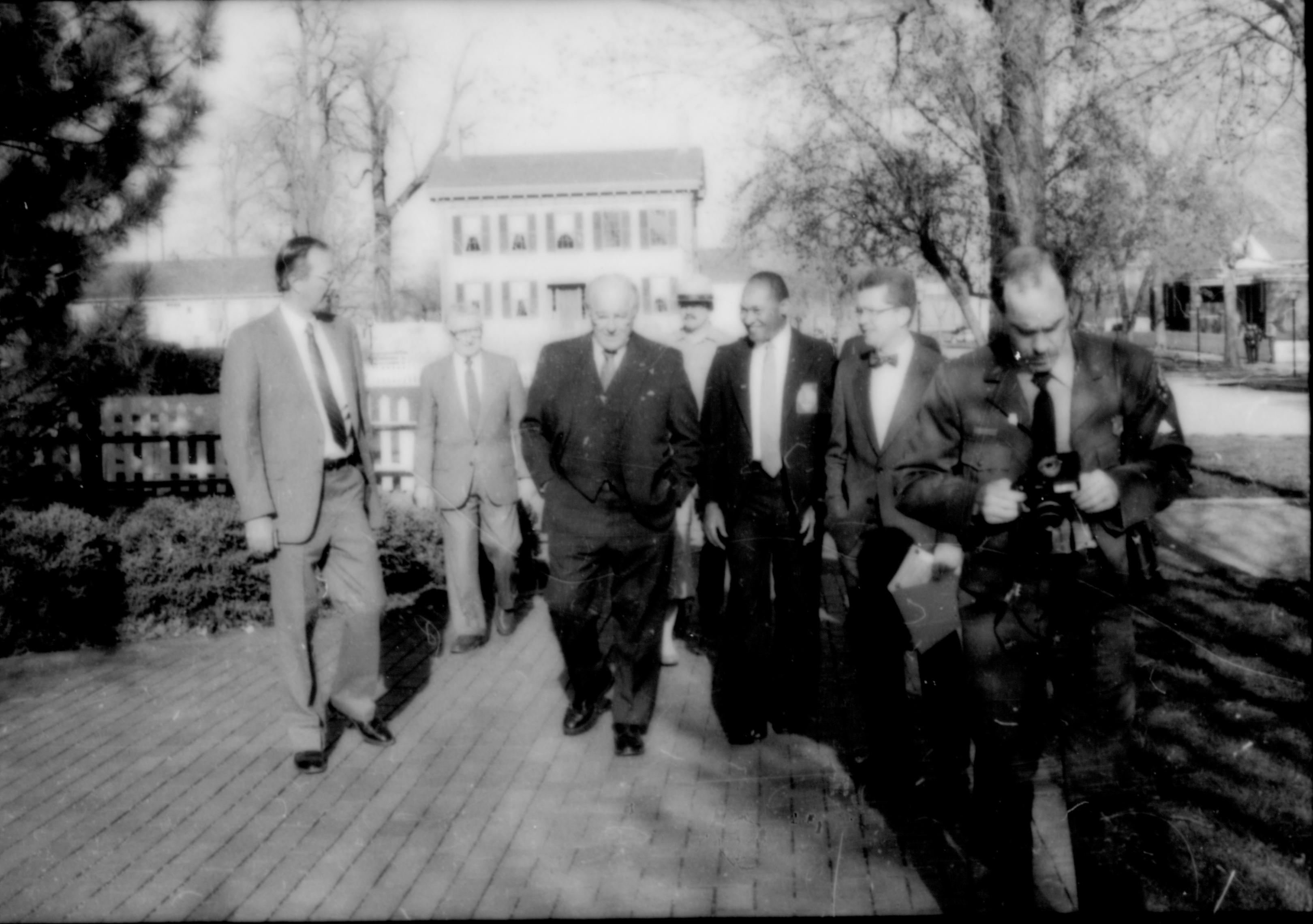 Group of men walking on brick walk by Visitor Center. Lincoln Home NHS- Paul Findley and Michel VIP visit, 128 Finley, Michel, visit, tour