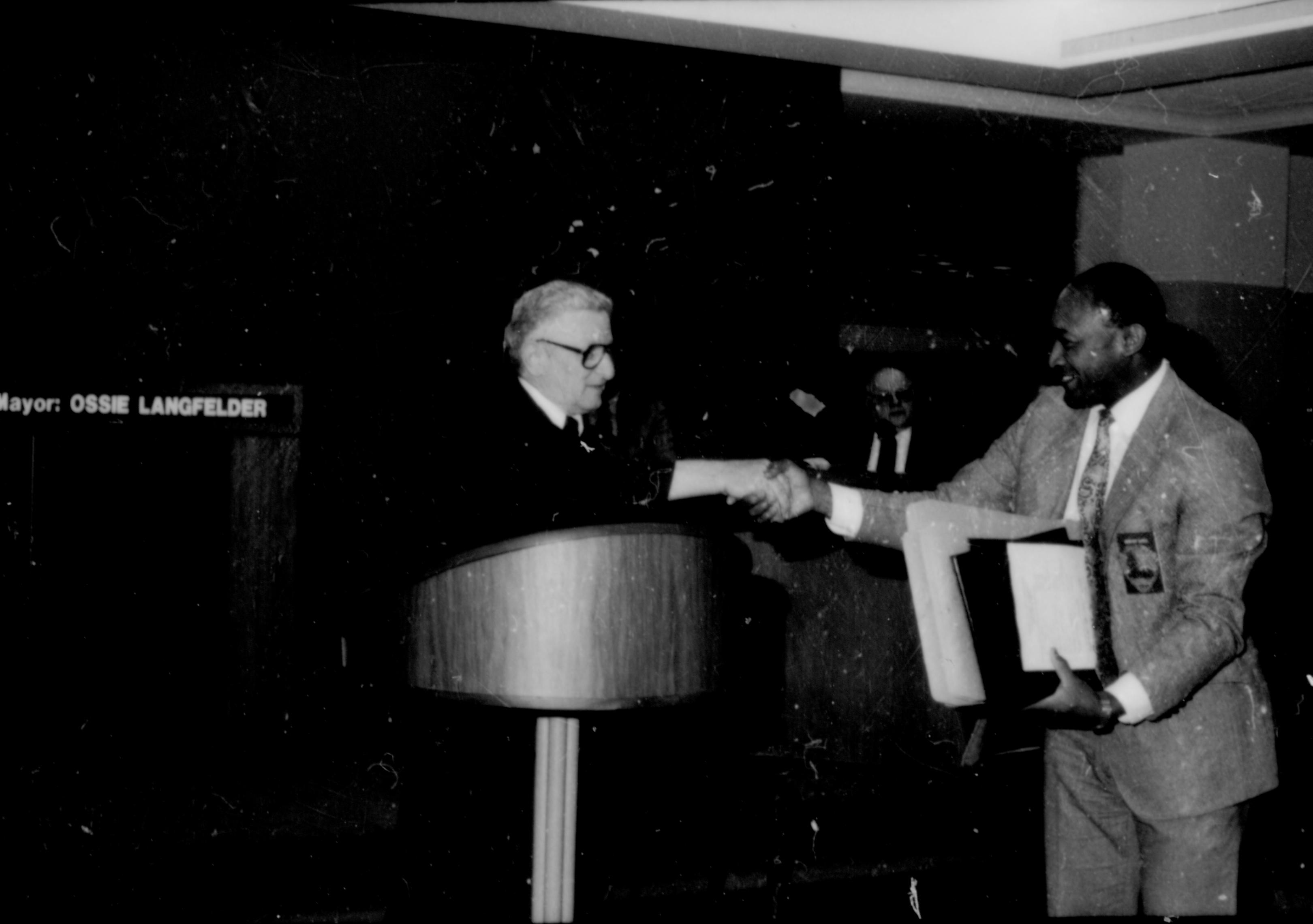 Man shaking hands with another at podium. Lincoln Home NHS- City Council Ollie Christmas Award, 133 Award, program