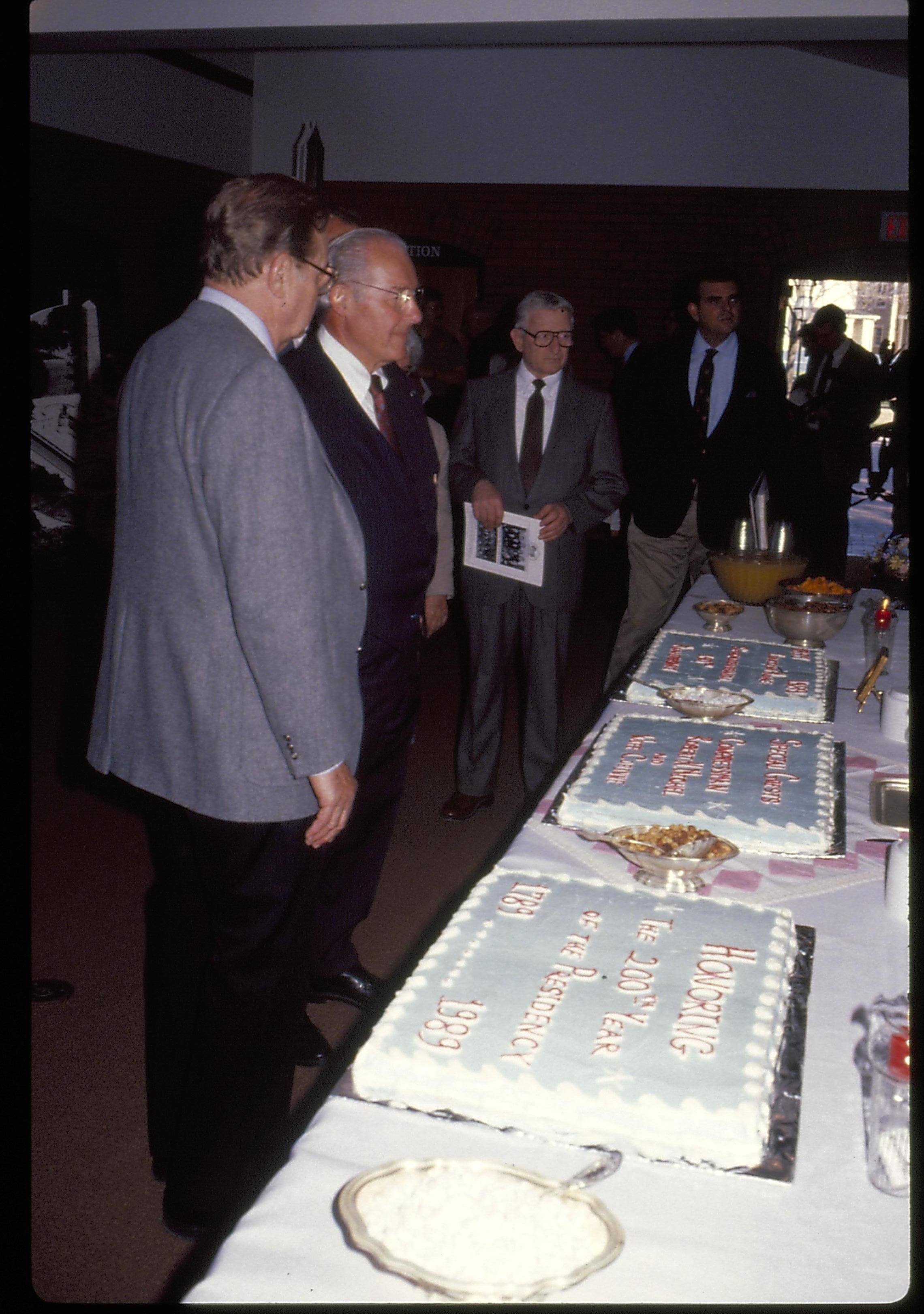 Men standing in front of tabke looking at cakes. Lincoln Home NHS- VIP Findley and Michel Visit award, visit, reception