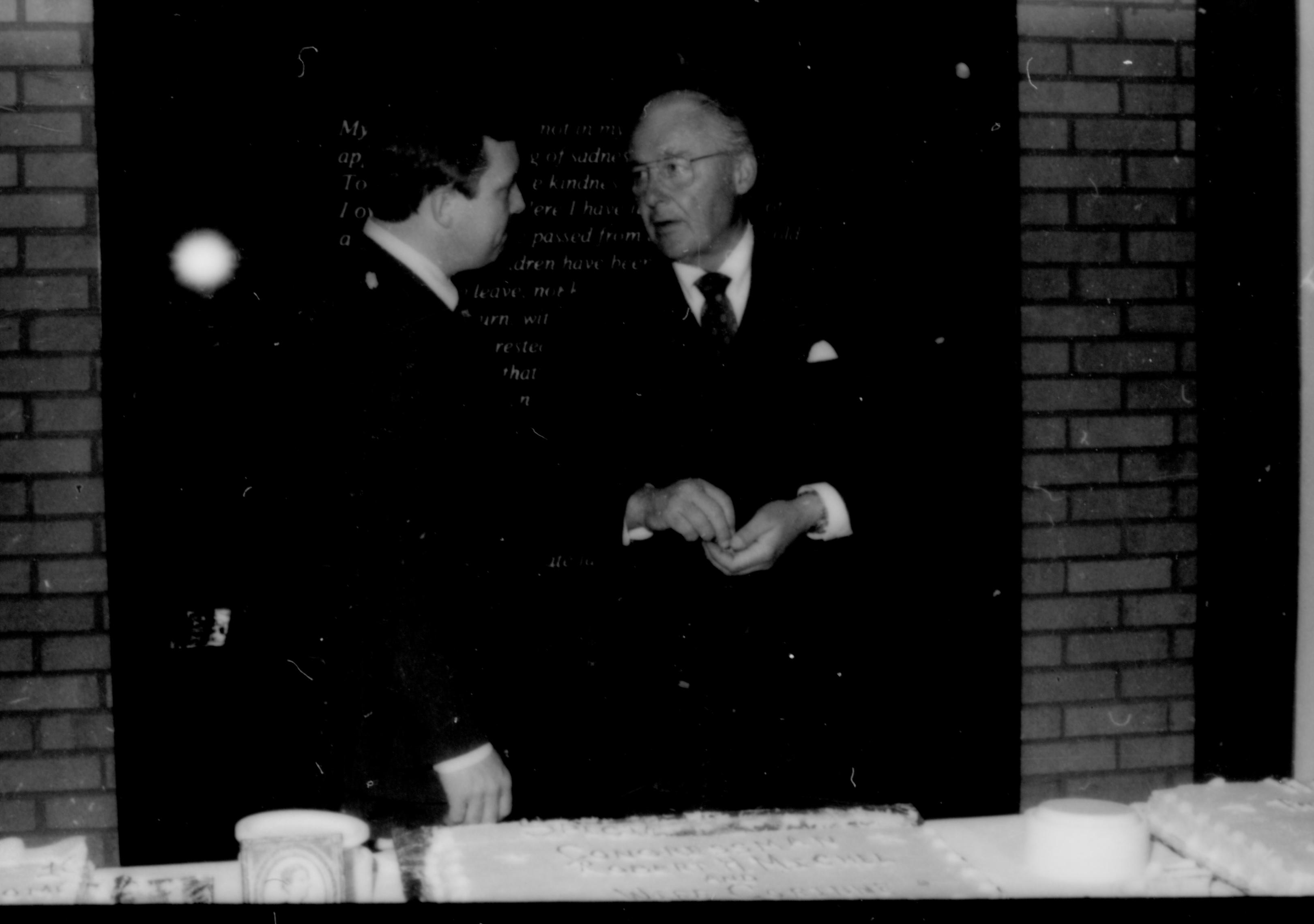 Two men conversing behind table. Lincoln Home NHS- Paul Findley and Michel VIP visit, 119 Finley, Michel, visit, reception