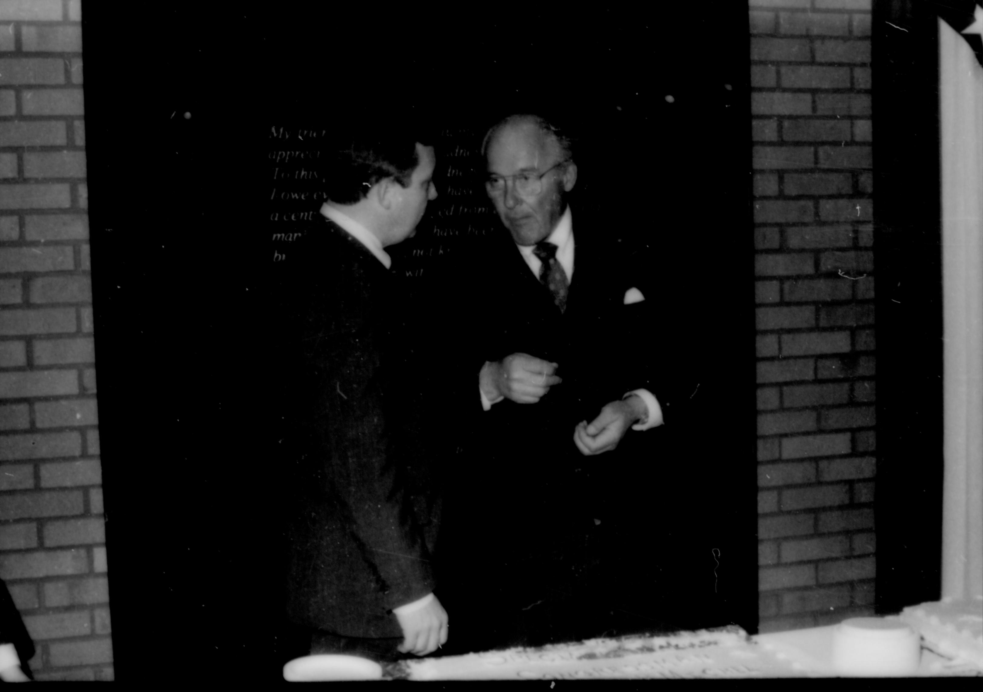 Two men conversing behind table. Lincoln Home NHS- Paul Findley and Michel VIP visit, 119 Finley, Michel, visit, reception