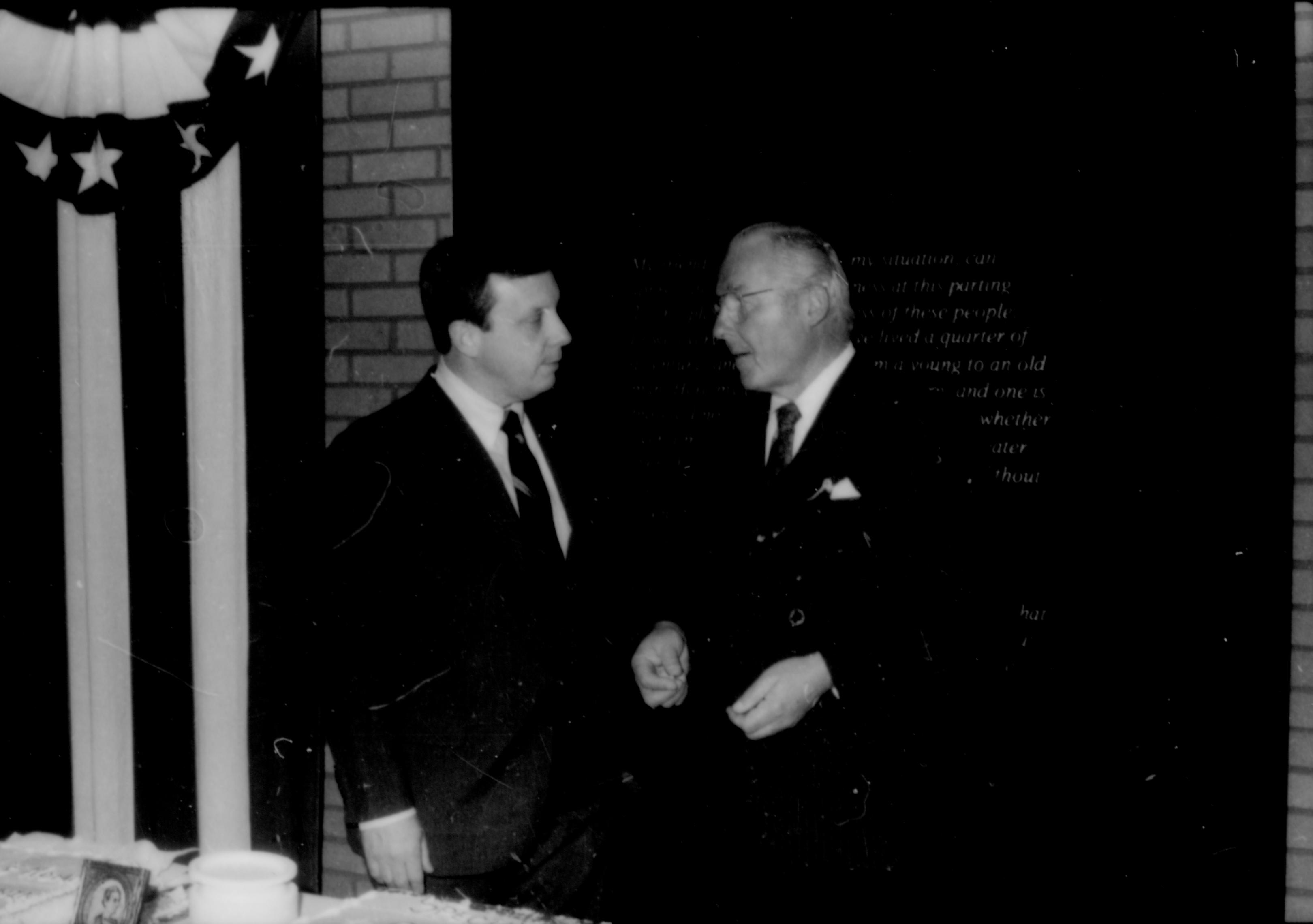 Two men conversing behind table. Lincoln Home NHS- Paul Findley and Michel VIP visit, 119 Finley, Michel, visit, reception