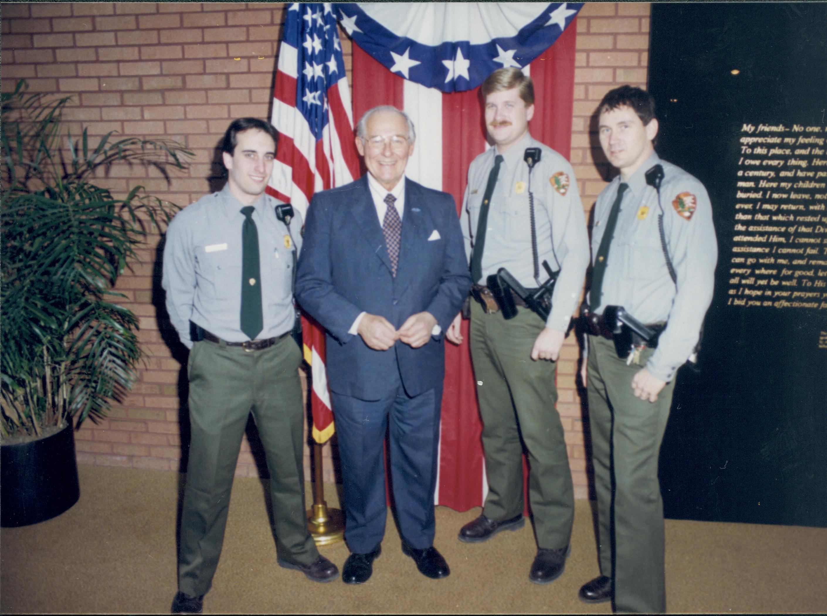 Three law enforcement rangers standing with man in front of flag & bunting. Lincoln Home NHS- VIP Findley and Michel Visit visit, program