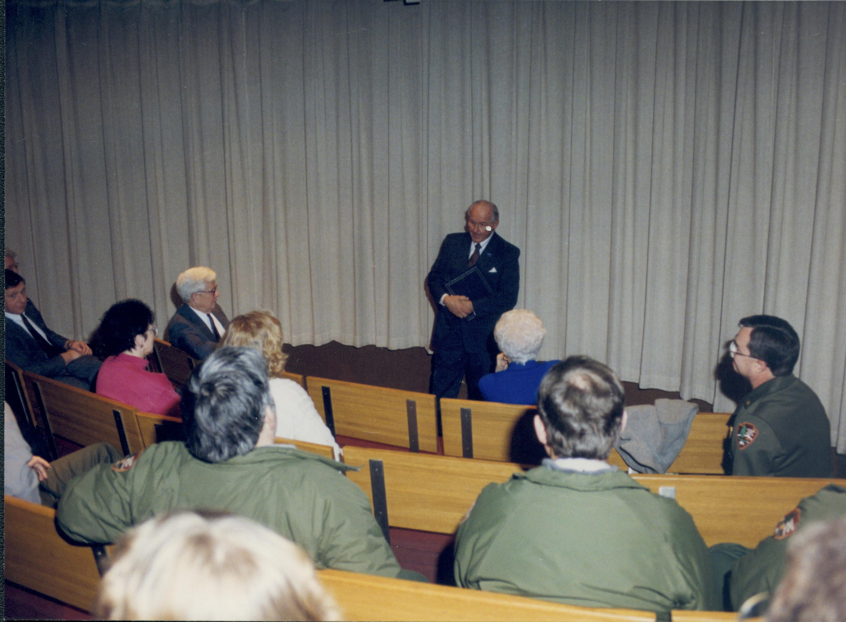 Man standing with hands folded in front of audience. Lincoln Home NHS- VIP Findley and Michel Visit visit, program, speech