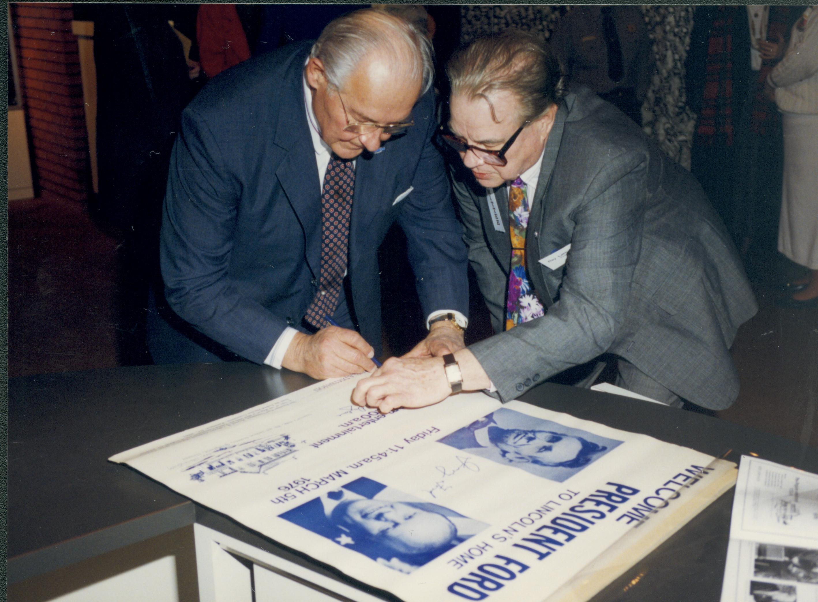 Two men, one signing poster. Lincoln Home NHS- VIP Findley and Michel Visit visit, program