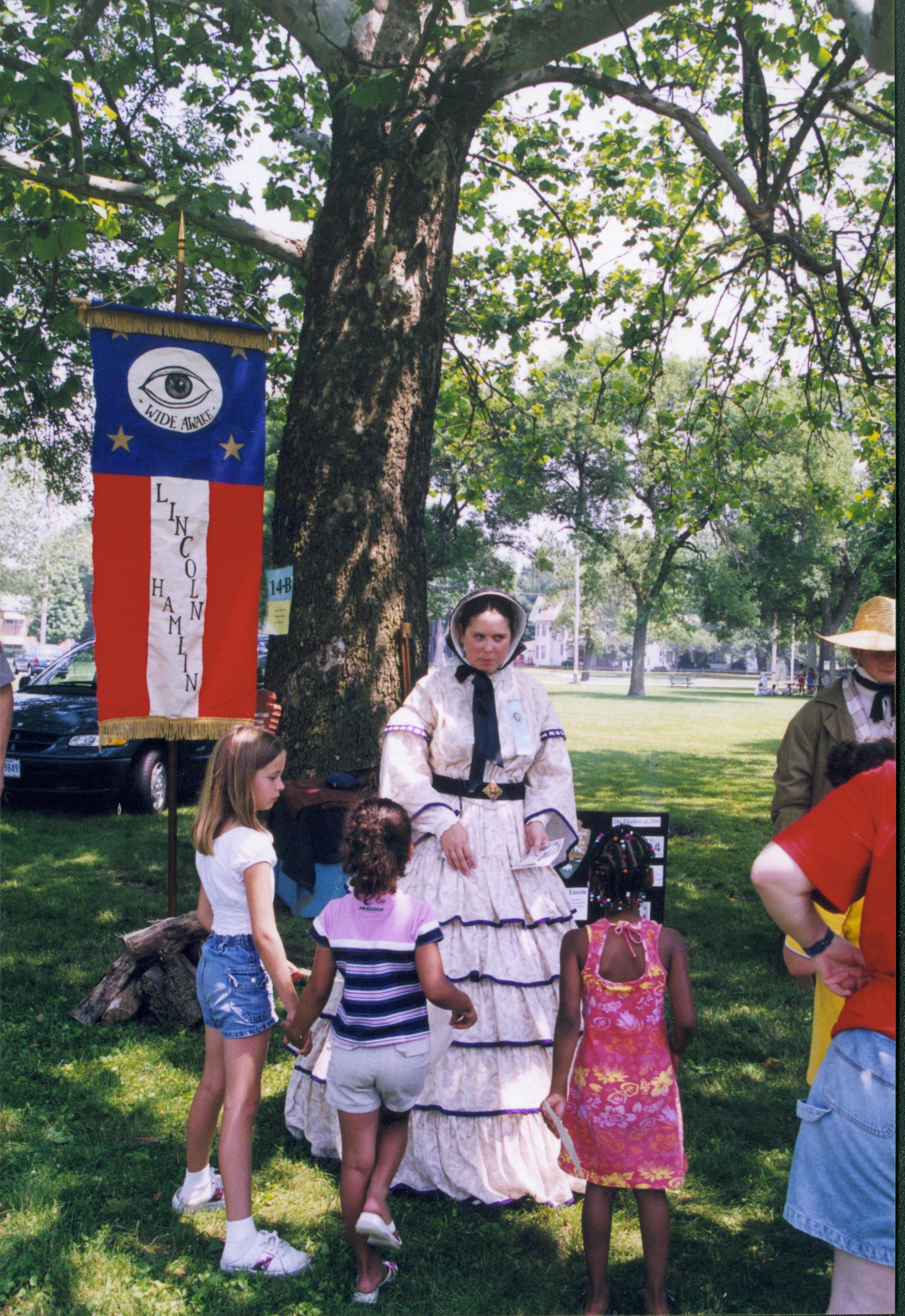 Lady in period dress talking with children in front of banner. Lincoln Home NHS- Grierson Days Jacksonville Grierson, Jacksonville, celebration