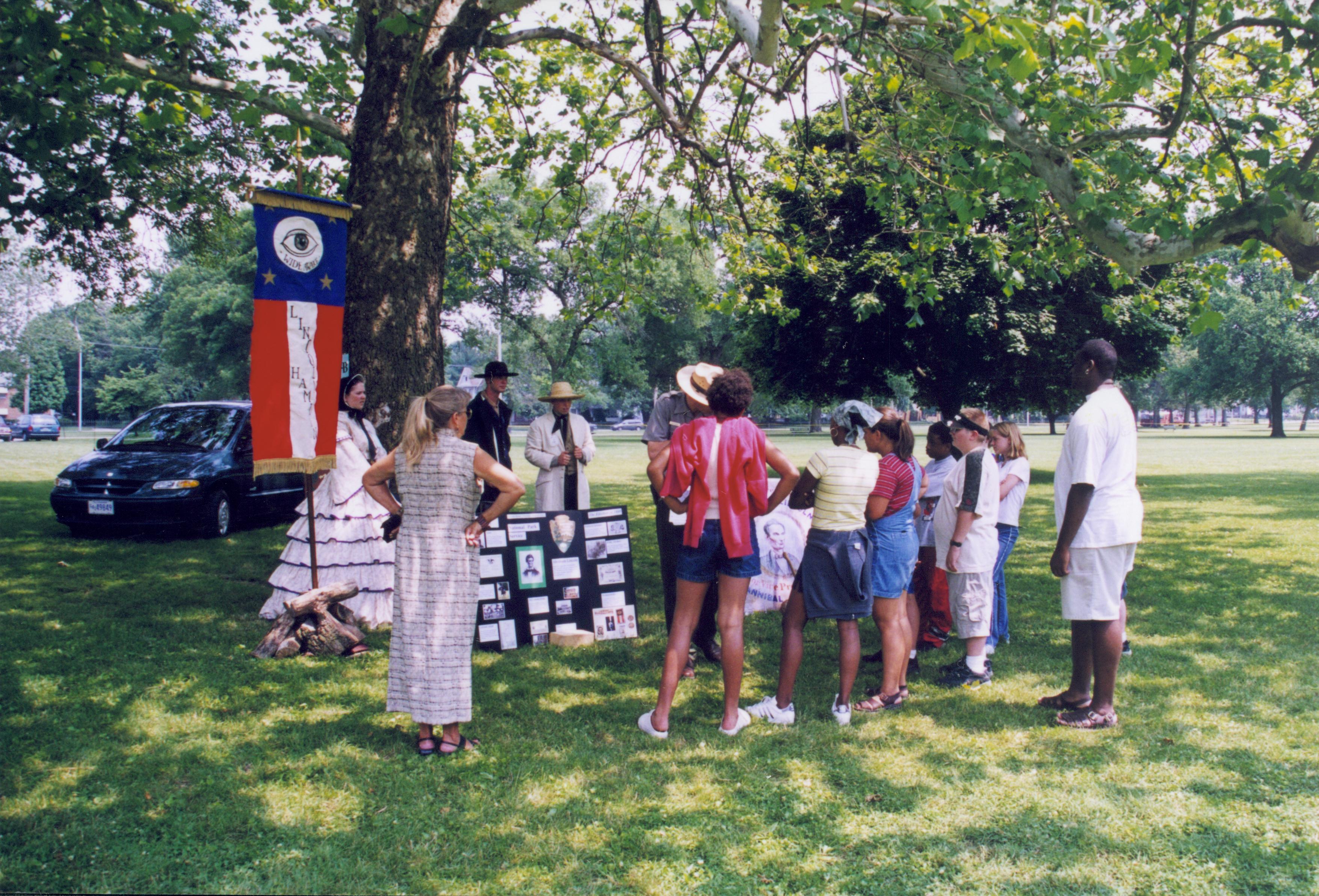 Distant shot of children listening to presentation under tree. Lincoln Home NHS- Grierson Days Jacksonville Grierson, Jacksonville, celebration