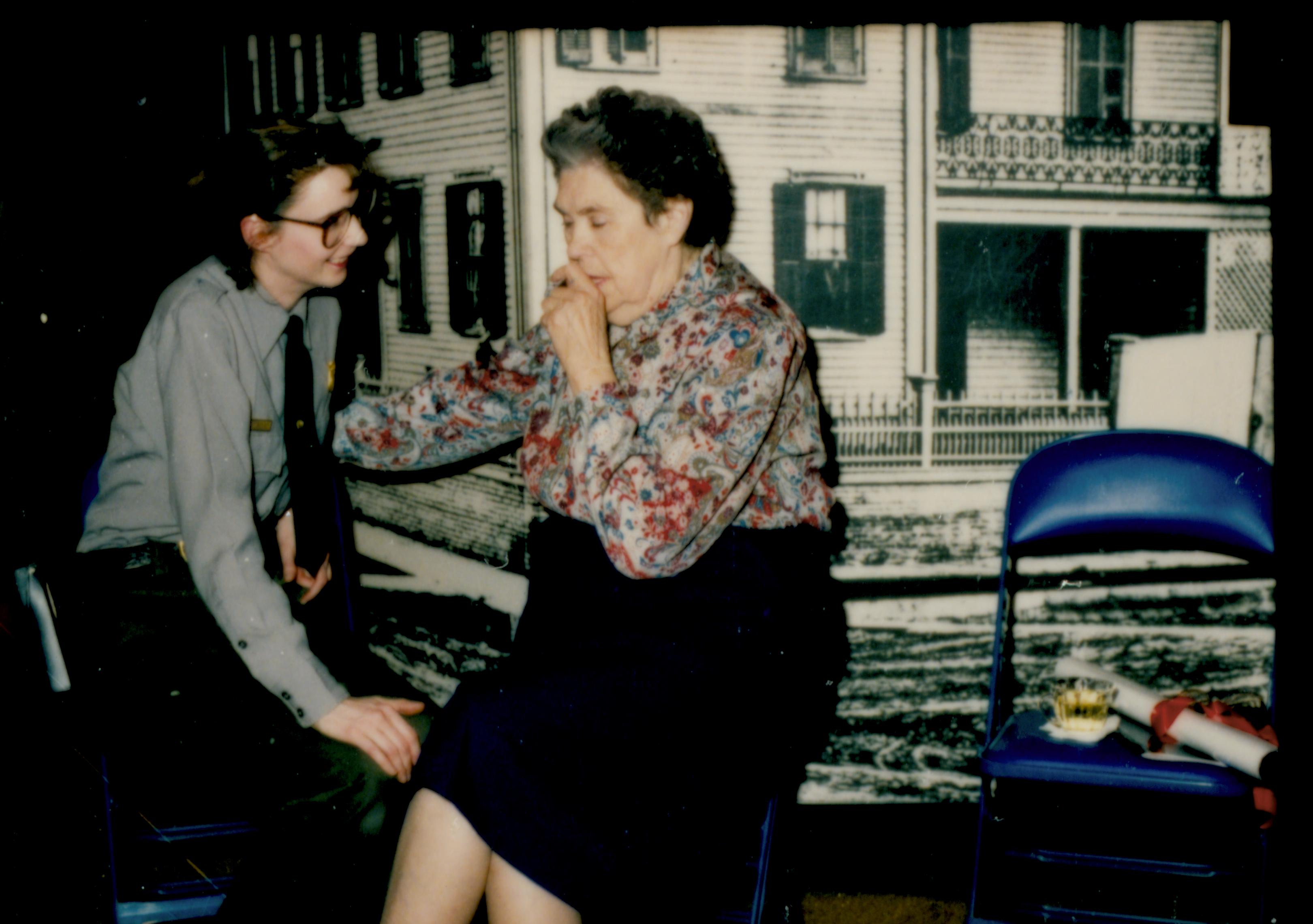 Ranger and lady seated in front of enlarged picture of home. Lincoln Home NHS- Author Ruth Ketchum visit, 11 Ketchum, visit