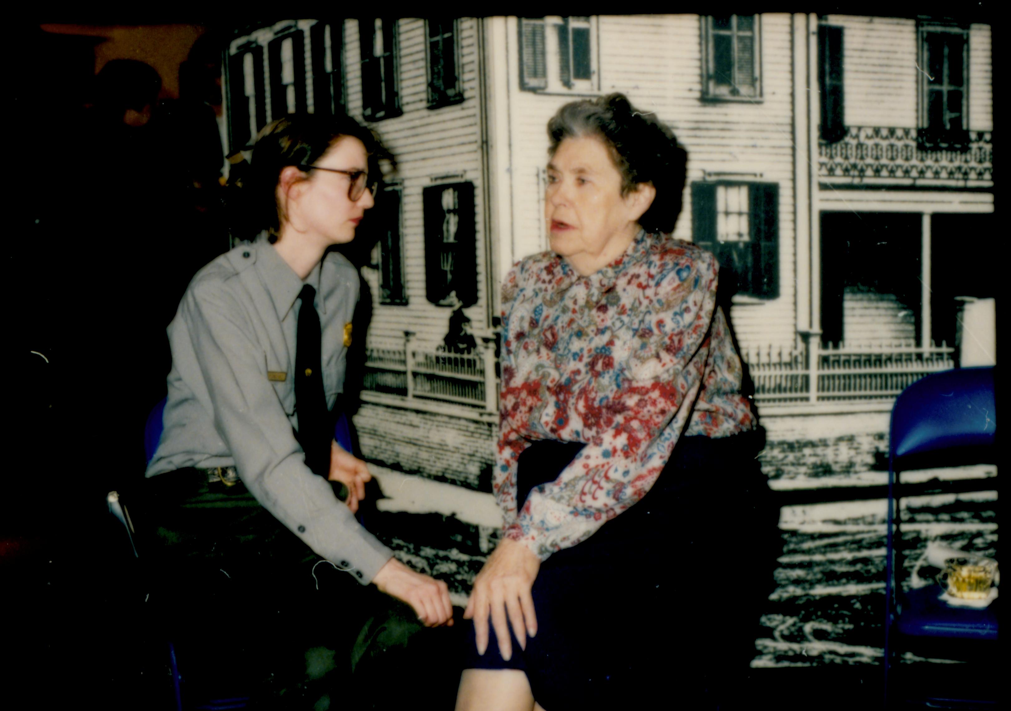 Ranger and lady seated in front of enlarged picture of home. Lincoln Home NHS- Author Ruth Ketchum visit, 11 Ketchum, visit