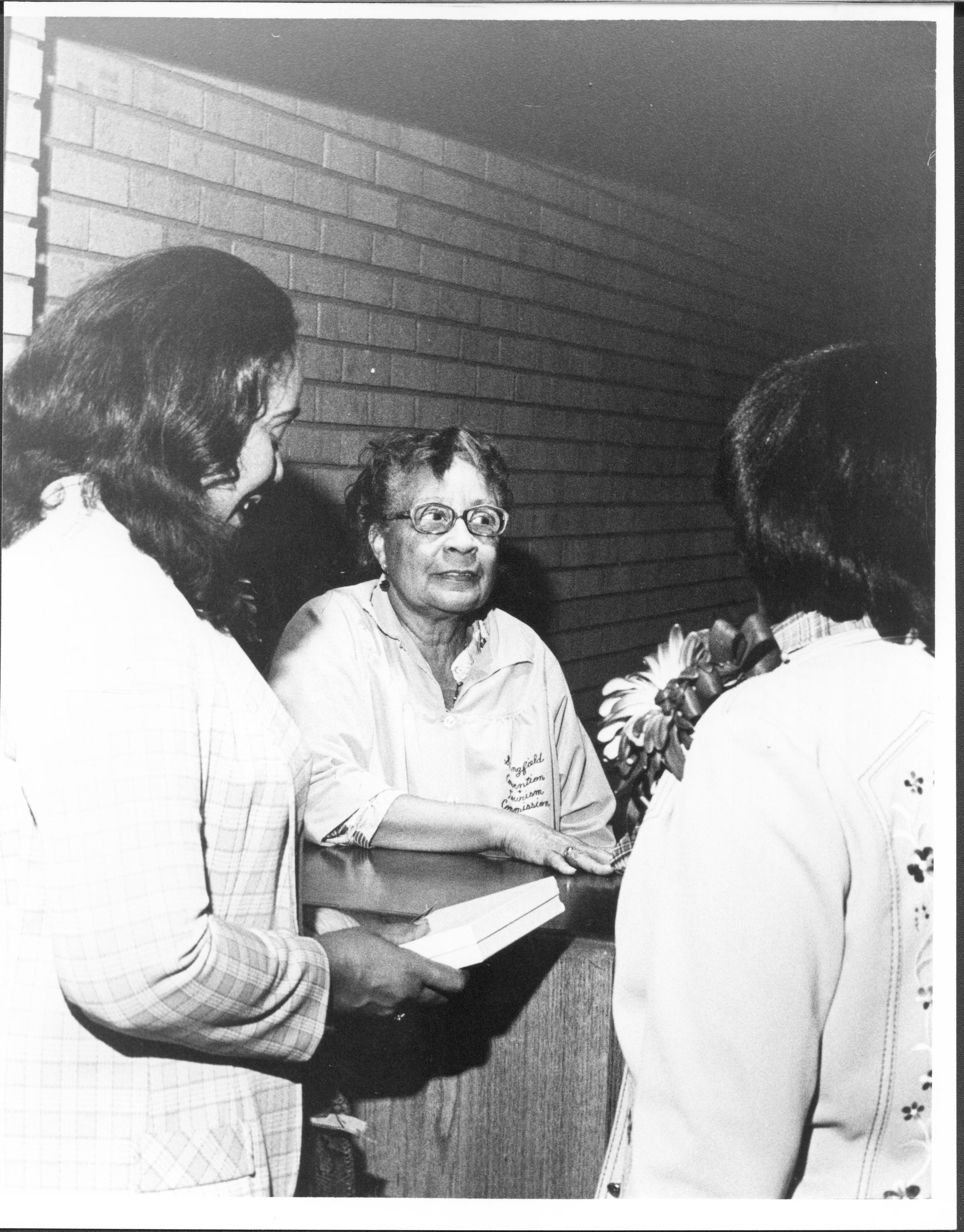 Three ladies standing, one holding two books.  Lincoln Home NHS- Coretta King Visit, 1000 King, visit, reception