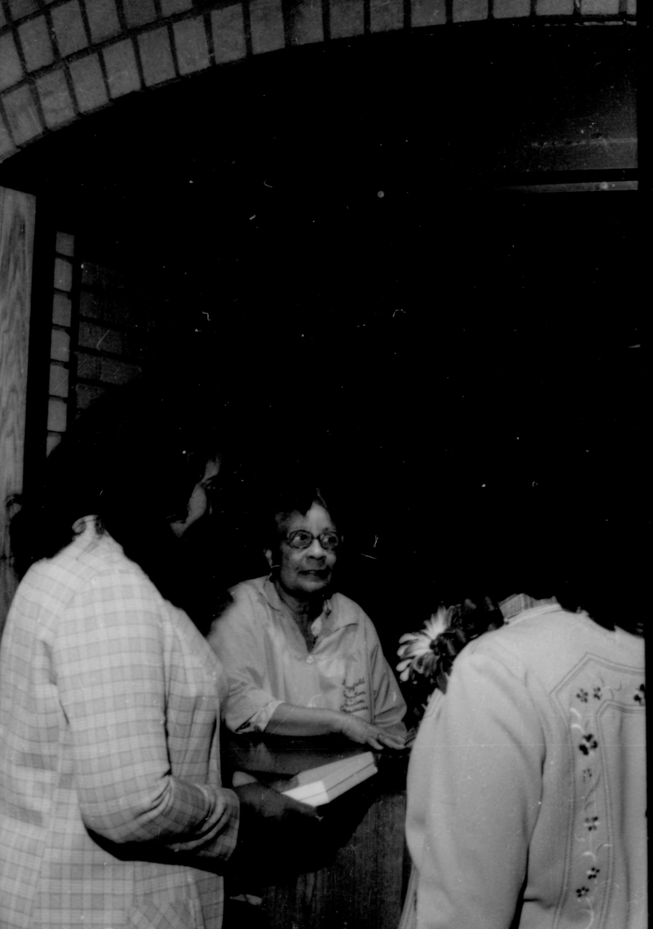 Three ladies standing, one holding two books.  Lincoln Home NHS- Coretta King Visit King, visit