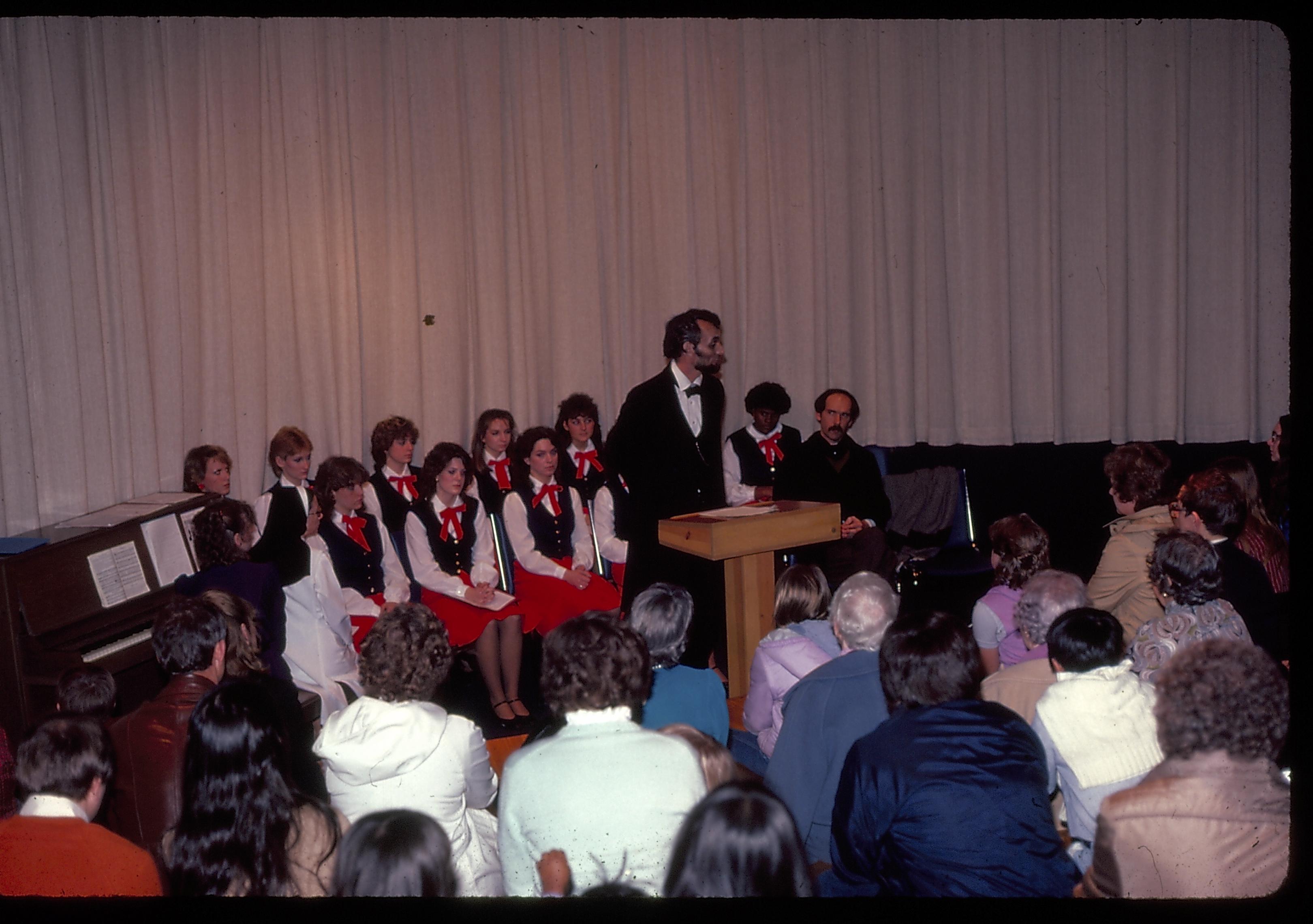 Lincoln impersonator speaking from podium. choral group seated behind. Lincoln Home NHS- Lincoln's Birthday 1984 birthday, Lincoln