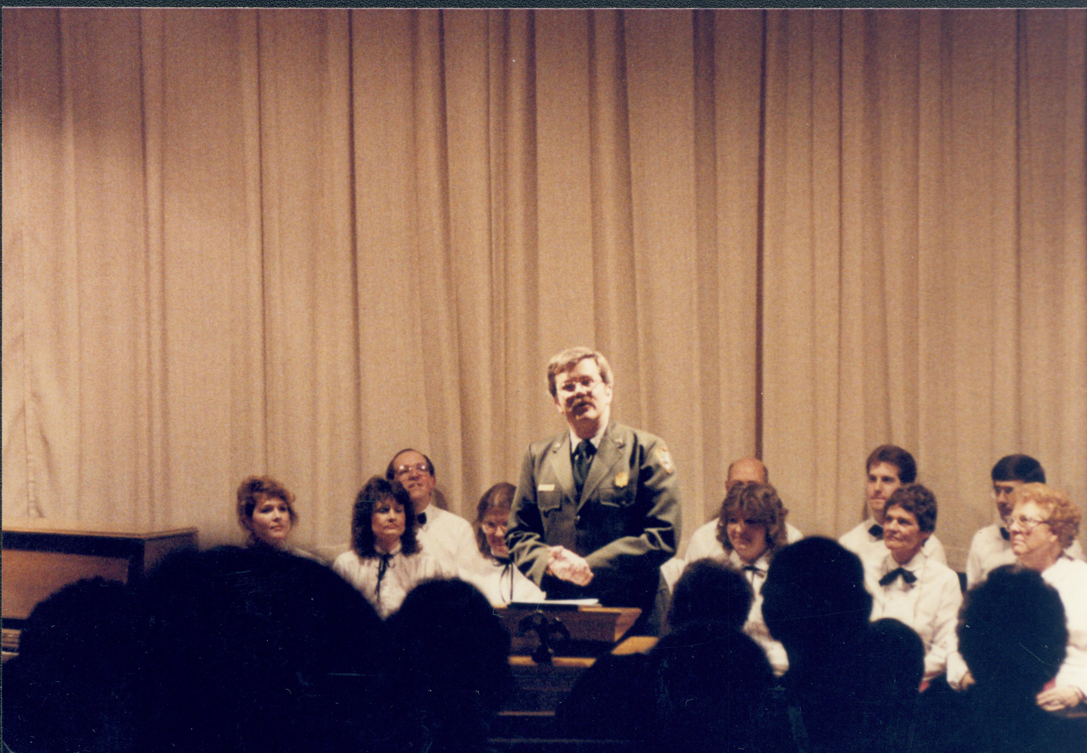 Ranger speaking from podium, choir seated behind. Lincoln Home NHS- Lincoln's Birthday 1988 birthday, Lincoln, Douglas