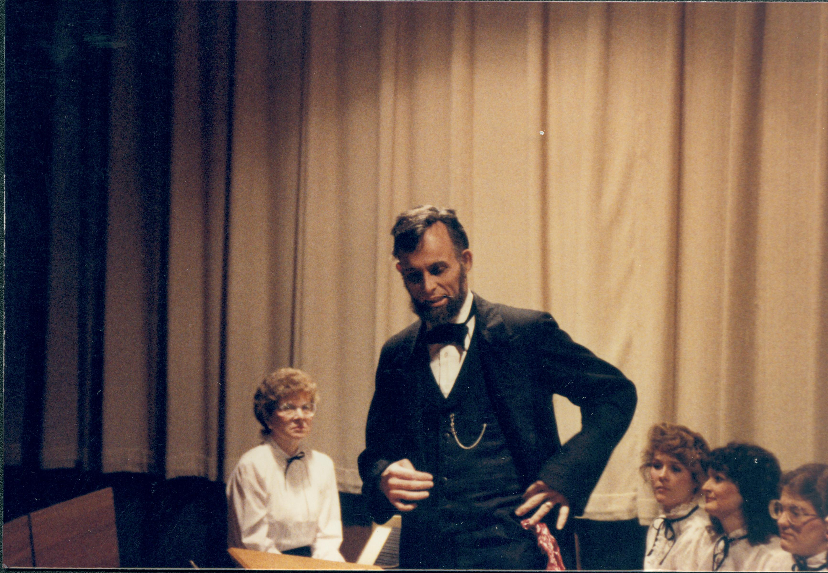 Lincoln impersonator speaking from podium, choral group seated behind. Lincoln Home NHS- Lincoln's Birthday 1988 birthday, Lincoln, Douglas