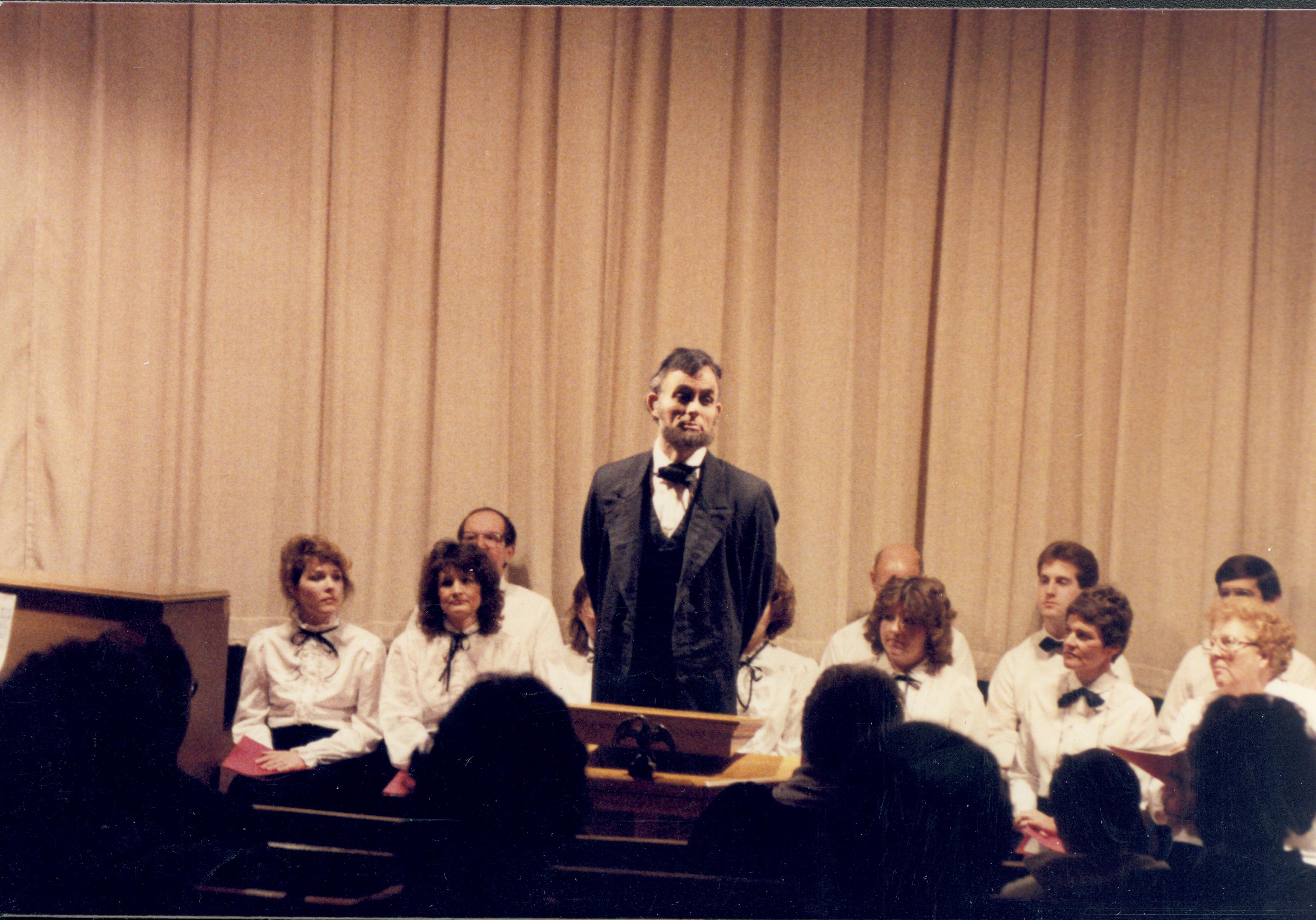 Lincoln impersonator speaking from podium, choral group seated behind. Lincoln Home NHS- Lincoln's Birthday 1988 birthday, Lincoln, Douglas