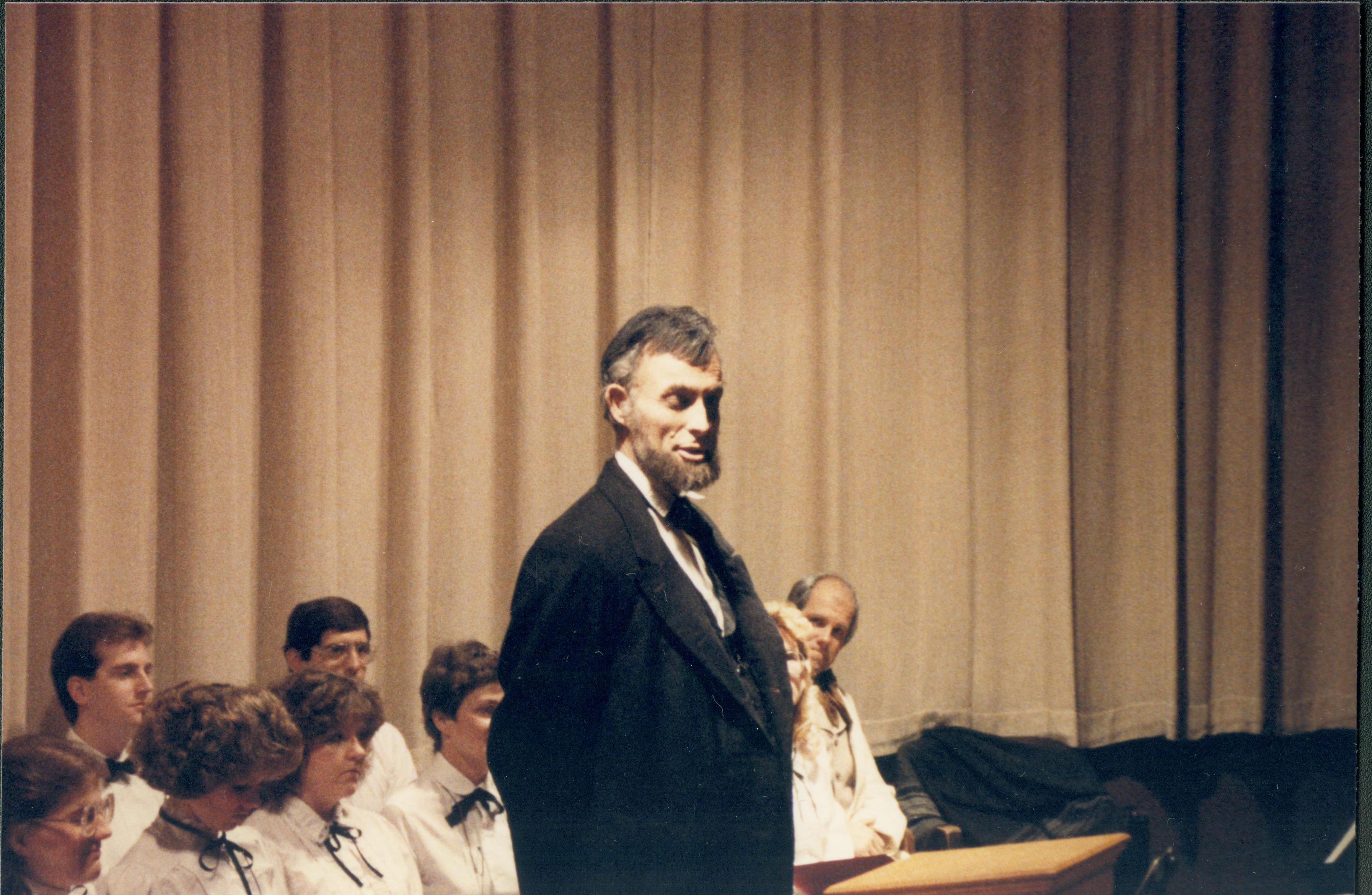 Lincoln impersonator speaking from podium, choral group seated behind. Lincoln Home NHS- Lincoln's Birthday 1988 birthday, Lincoln, Douglas