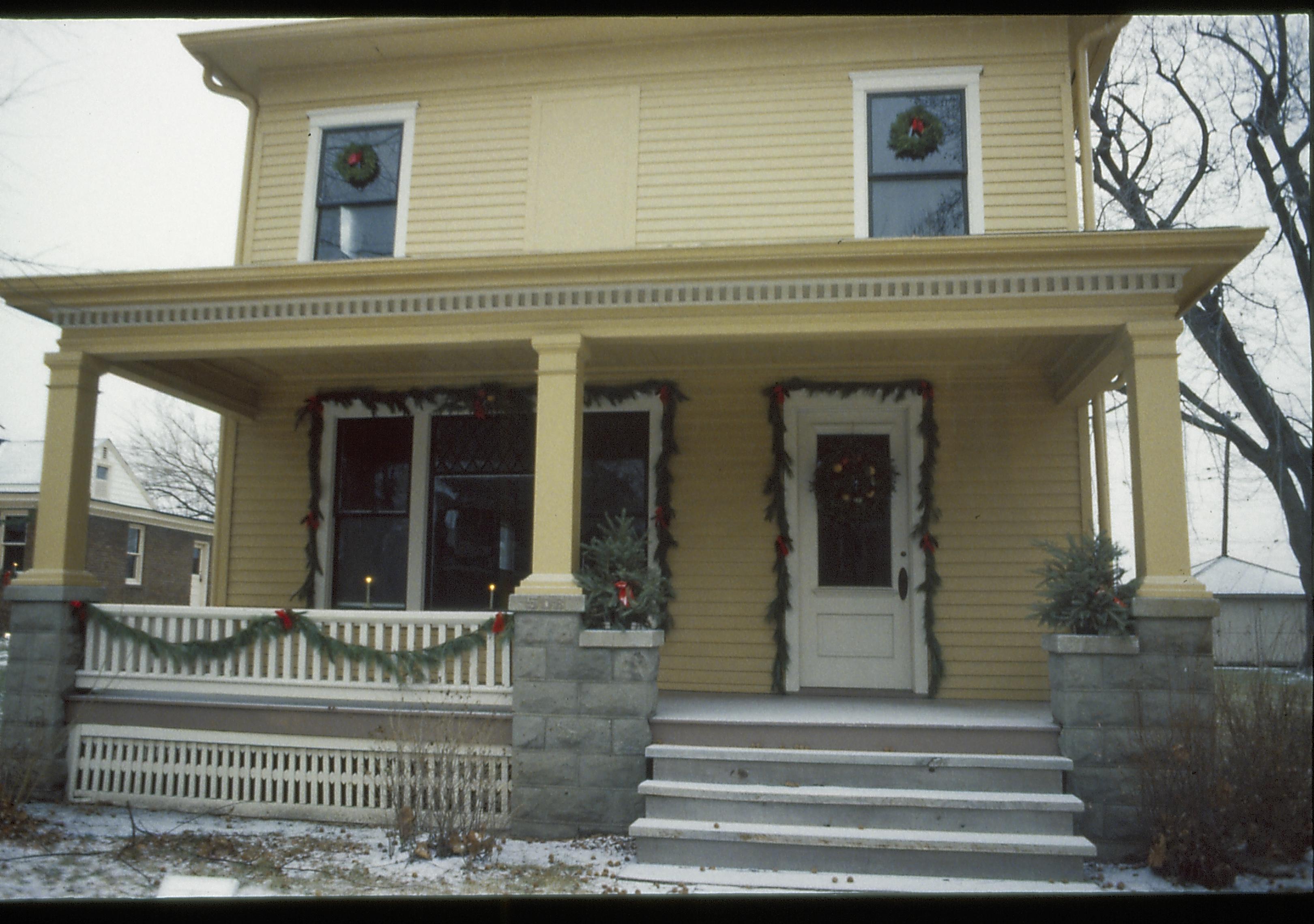 Lincoln Home NHS- Christmas in Lincoln Neighborhood Looking east from yard, Cook house and porch decorated for Christmas, Arnold in background. Christmas, decorations, decor, Cook, Arnold, wreath, garland, snow, porch