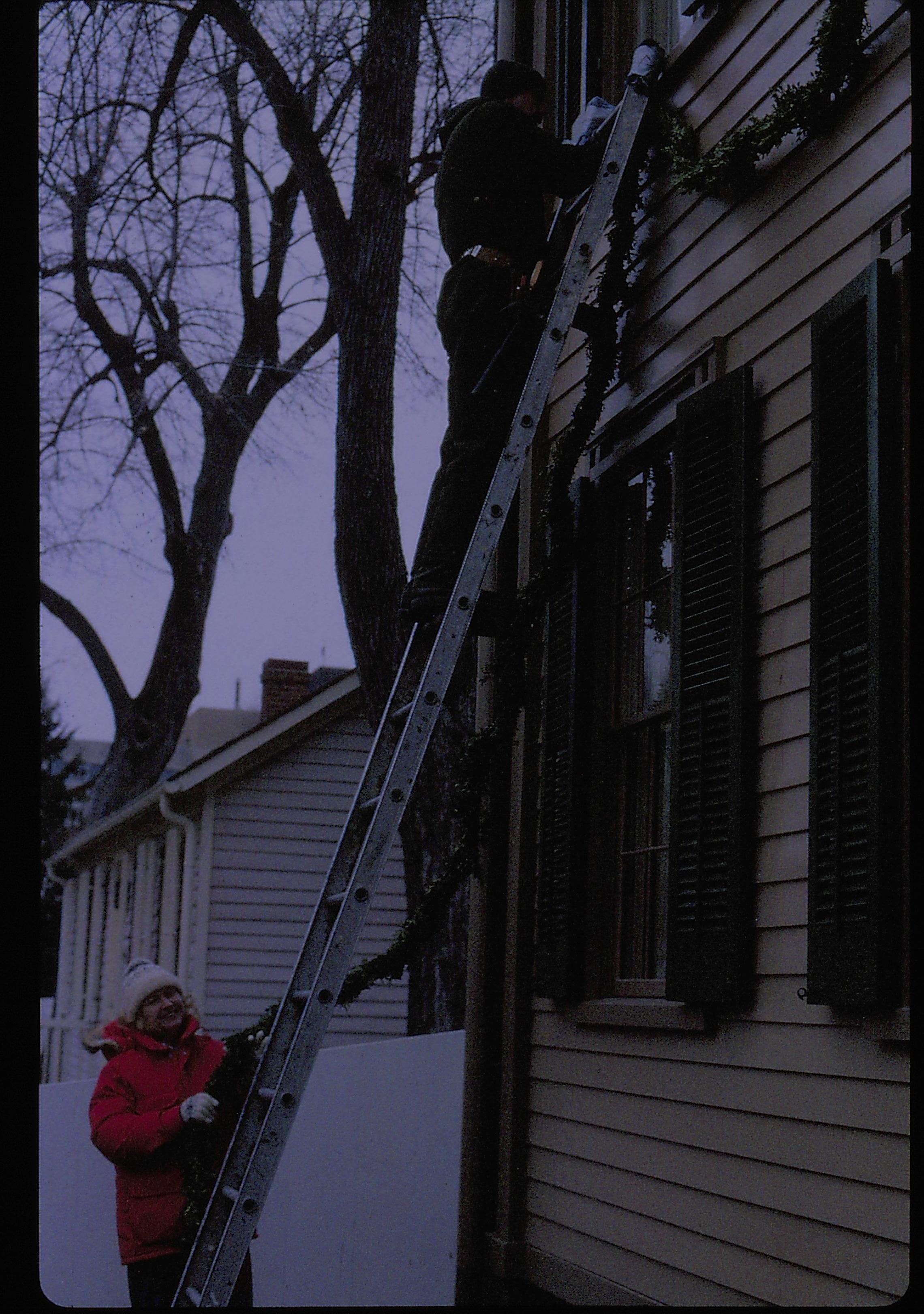 Lincoln Home NHS- Christmas in Lincoln Neighborhood Looking north, maintenance staff hanging garland on Lincoln home west face. Detail. Christmas, decorations, Lincoln, staff, ladder, garland