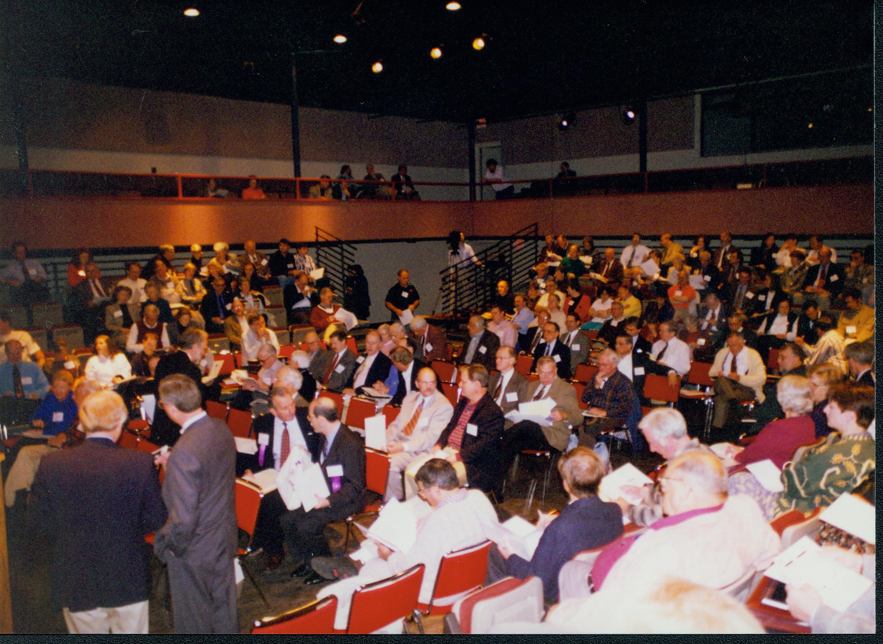 Two men standing, audience seated. 1-1997 Colloq (color); 10 Colloquium, 1997