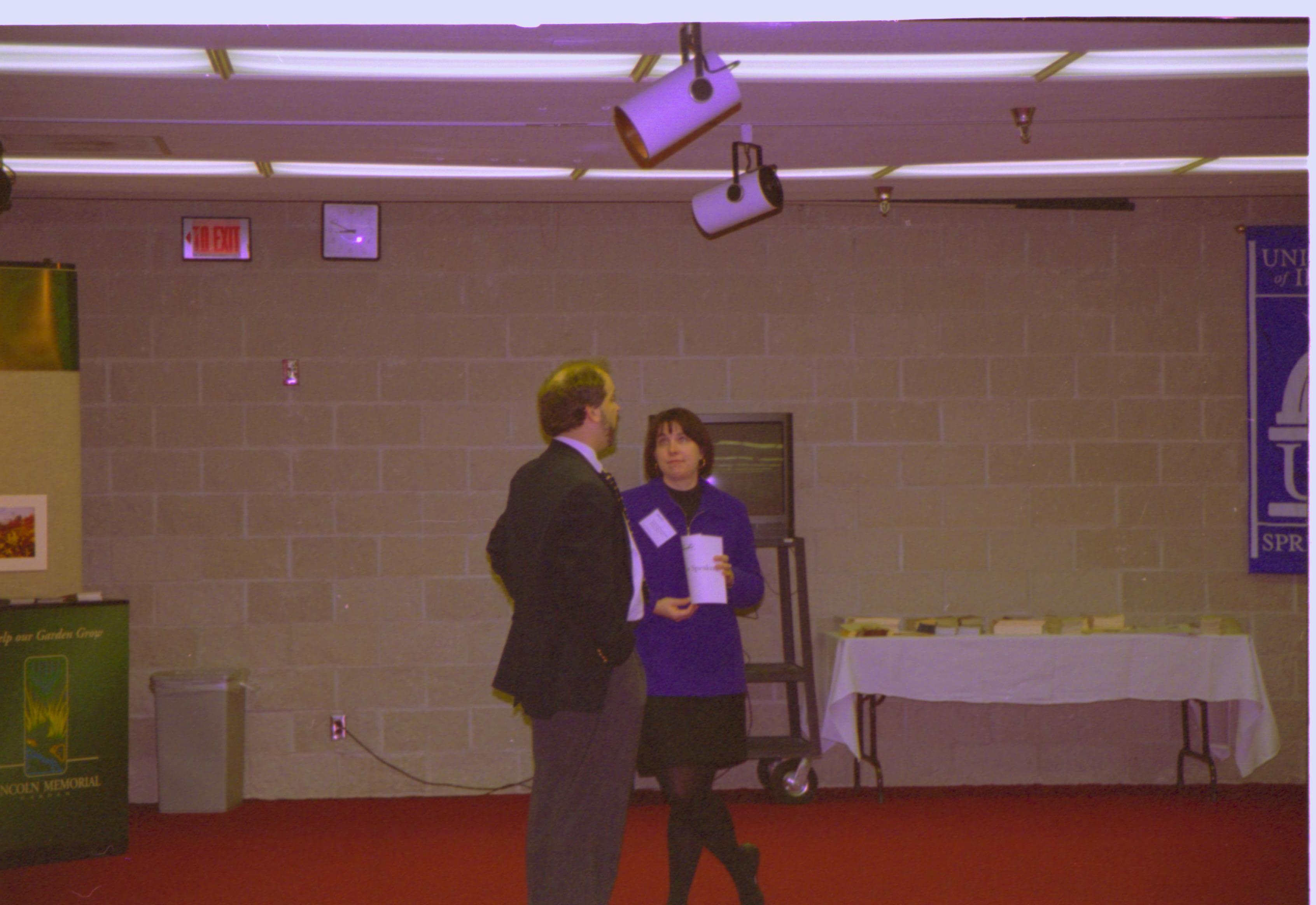 Man and woman talking in front of TV monitor. 4-1997 Colloq (color); 4 Colloquium, 1997