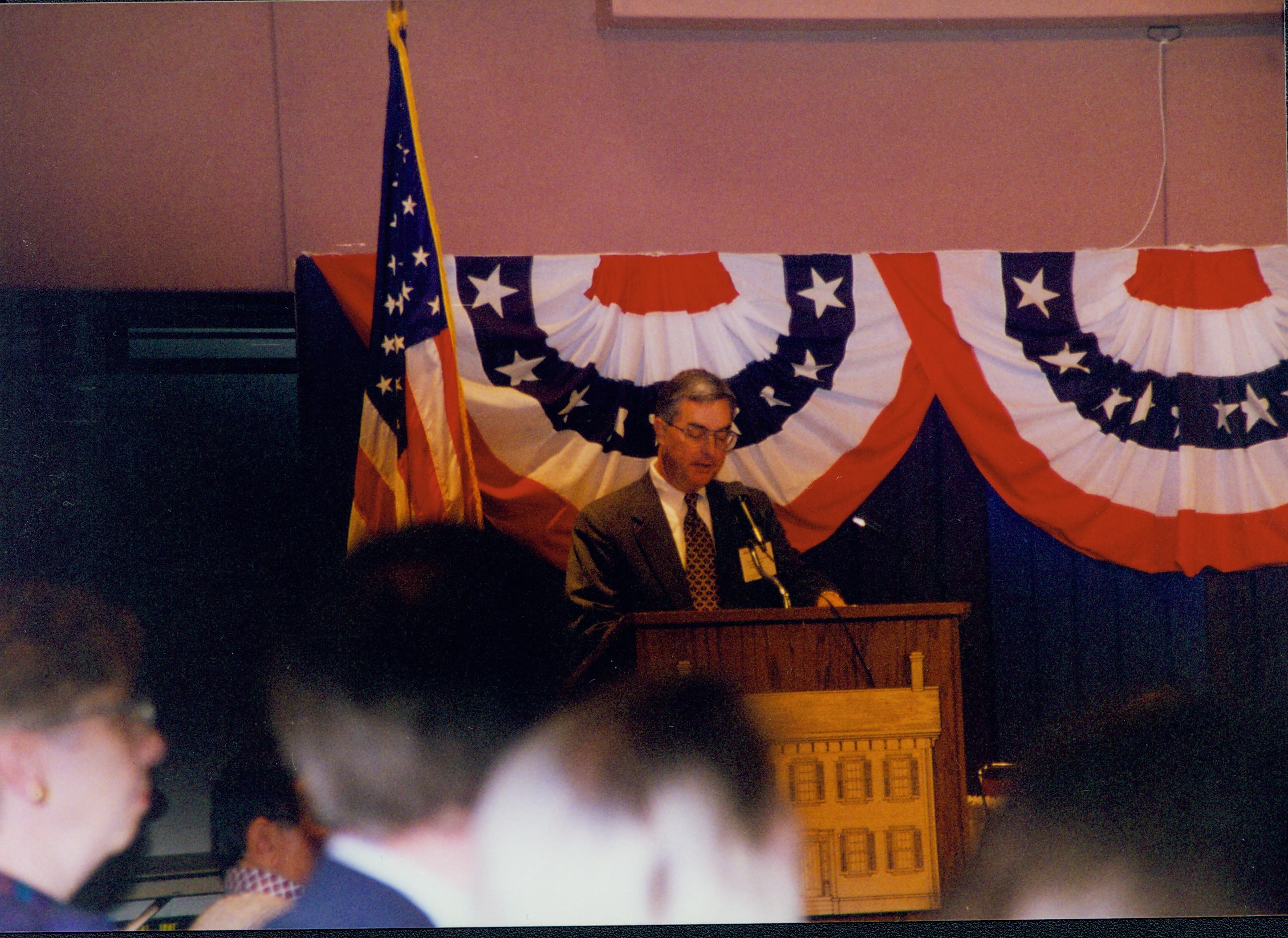 Man at posium with bunting hung behind. 1-1997 Colloq (color); 14 Colloquium, 1997