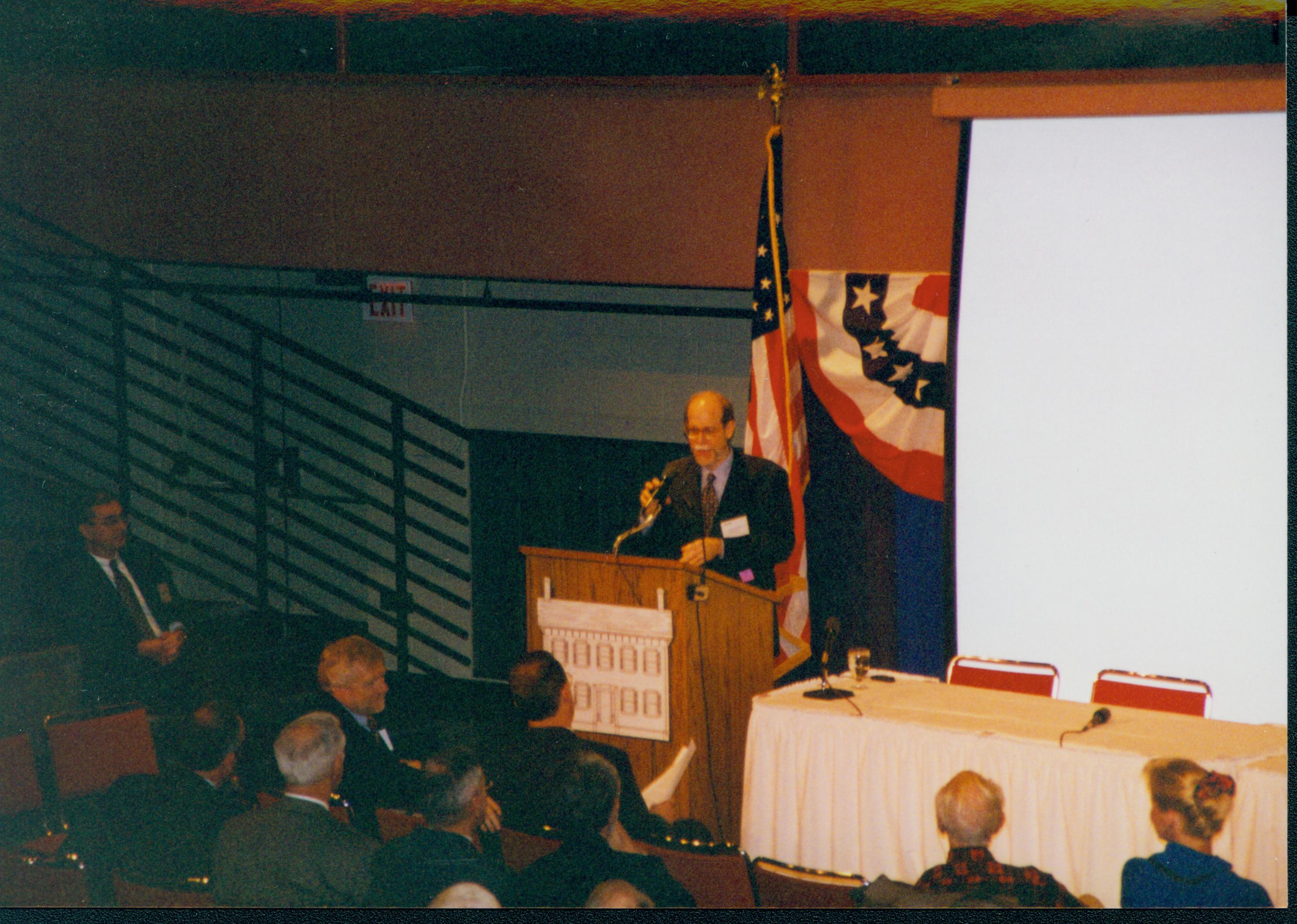 Man speaking, screen behind him. 1-1997 Colloq (color); 25 Colloquium, 1997